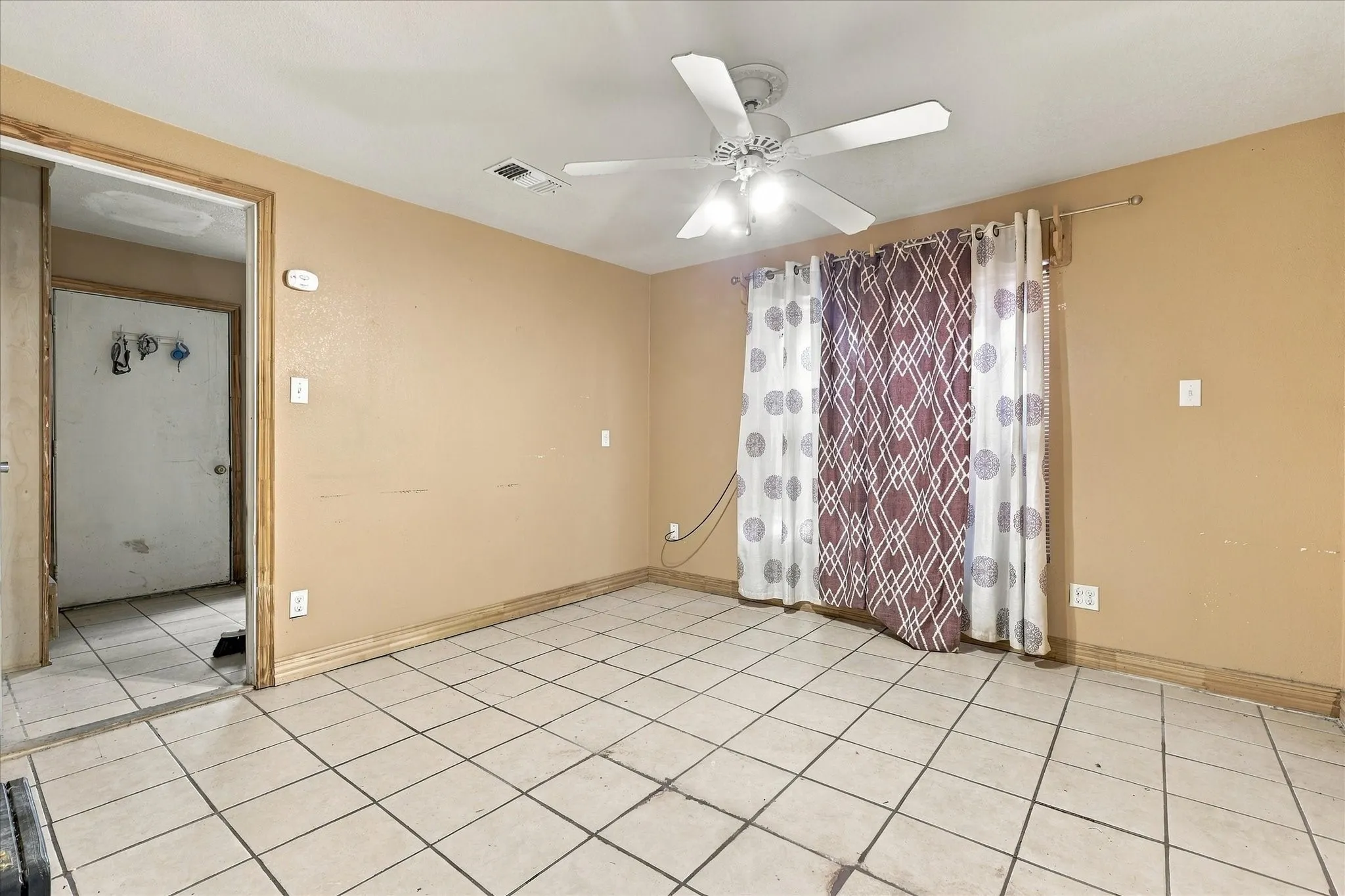 Interior space featuring light-toned ceramic tile flooring and a ceiling-mounted fan with integrated lighting