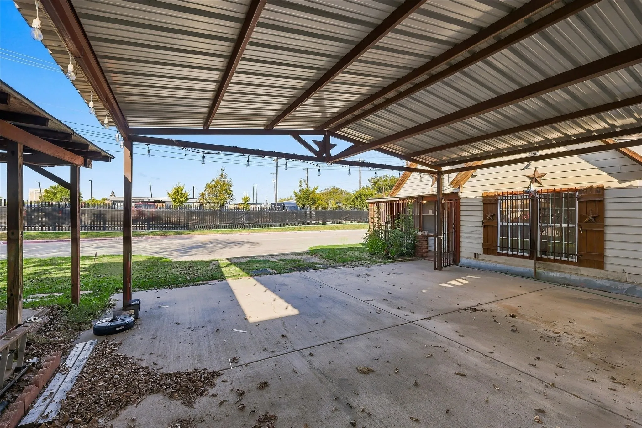 Covered carport with metal roofing, structural steel framing, concrete flooring, and exterior siding