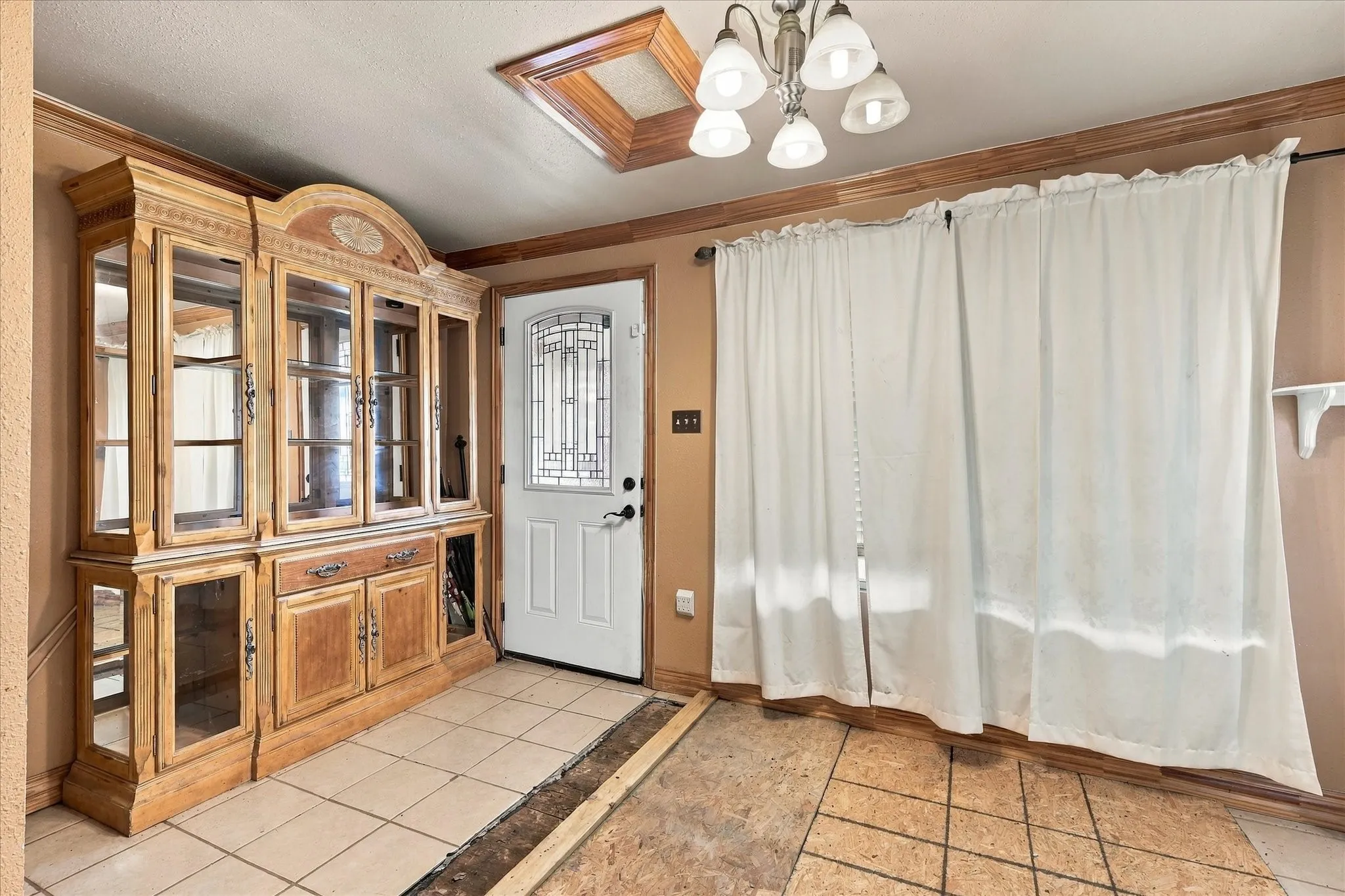Built-in wood cabinetry, exterior door with decorative glass insert, skylight with wood trim, and five-arm chandelier light fixture
