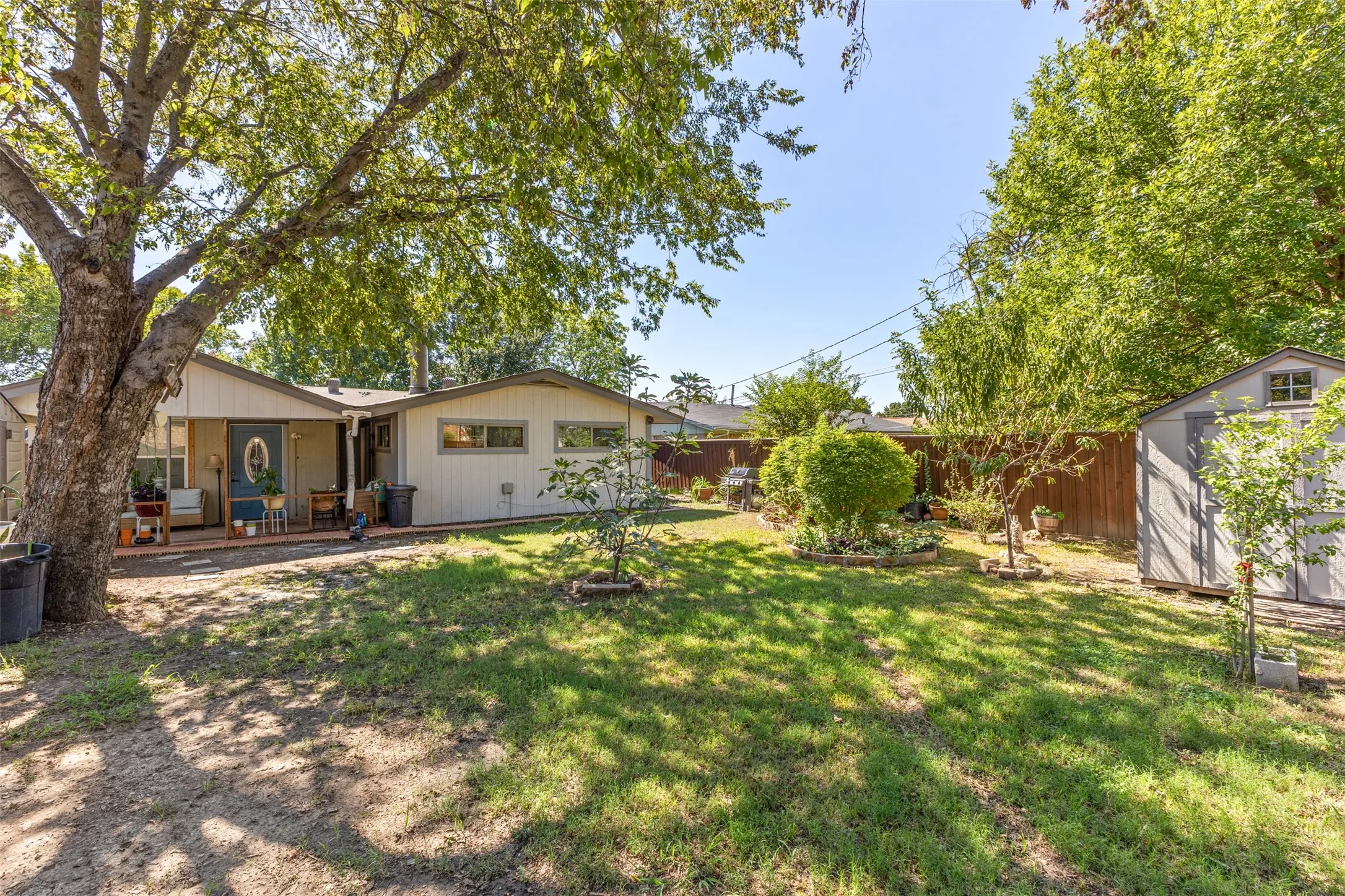 Backyard featuring a covered patio, mature trees, wood privacy fencing, and a detached storage shed