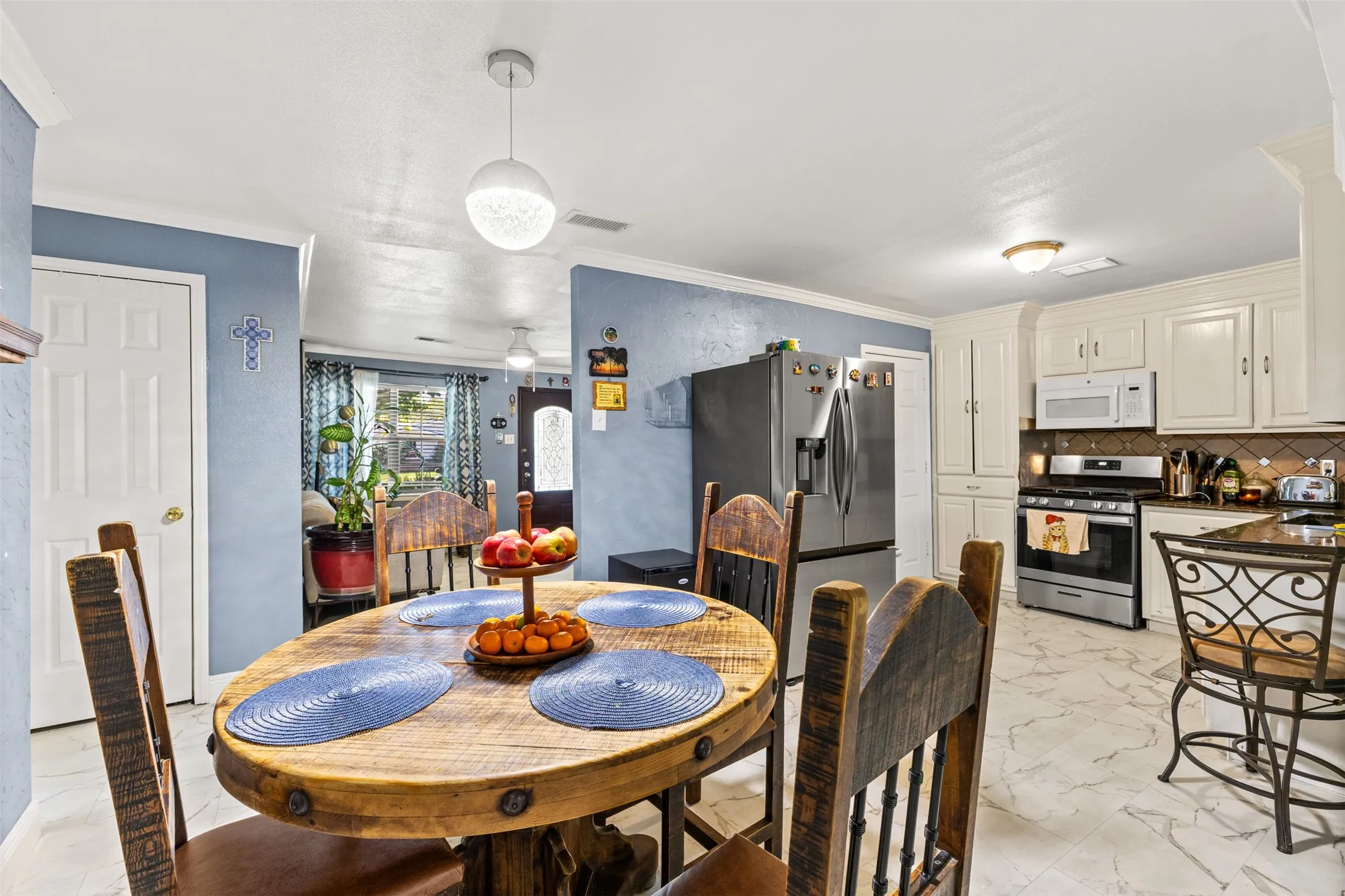 Kitchen featuring white shaker-style cabinetry, stainless steel appliances, stone-look tile flooring, and a contemporary spherical pendant light