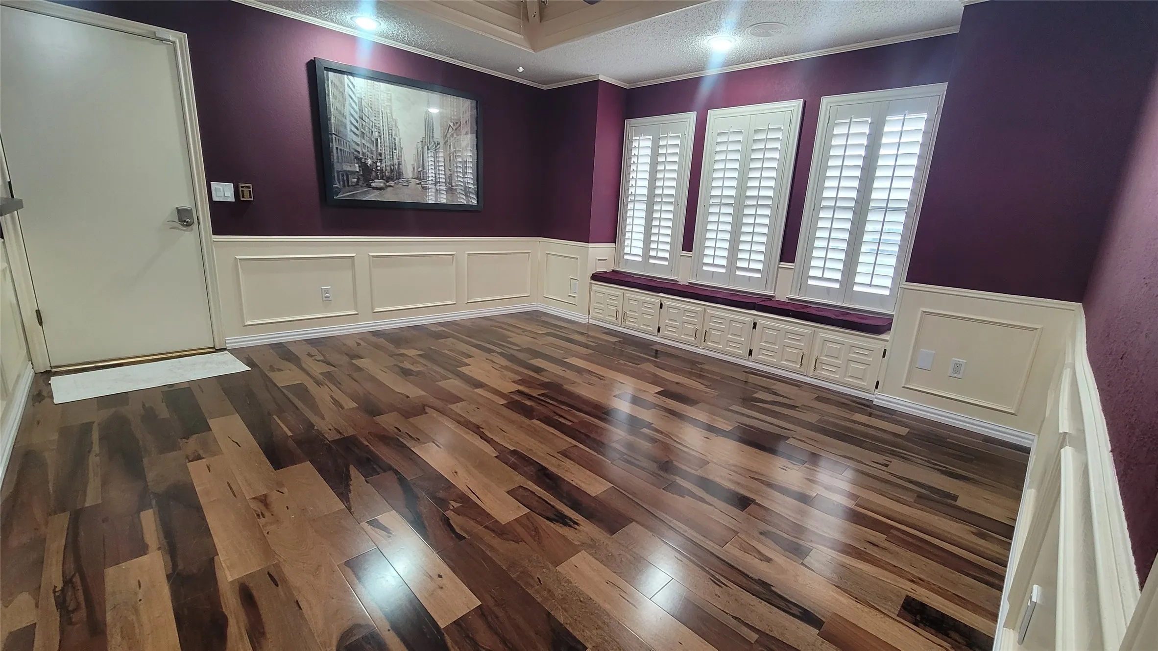 Wood-finish flooring, custom built-in window seating, wall-to-wall wainscoting, and plantation shutters