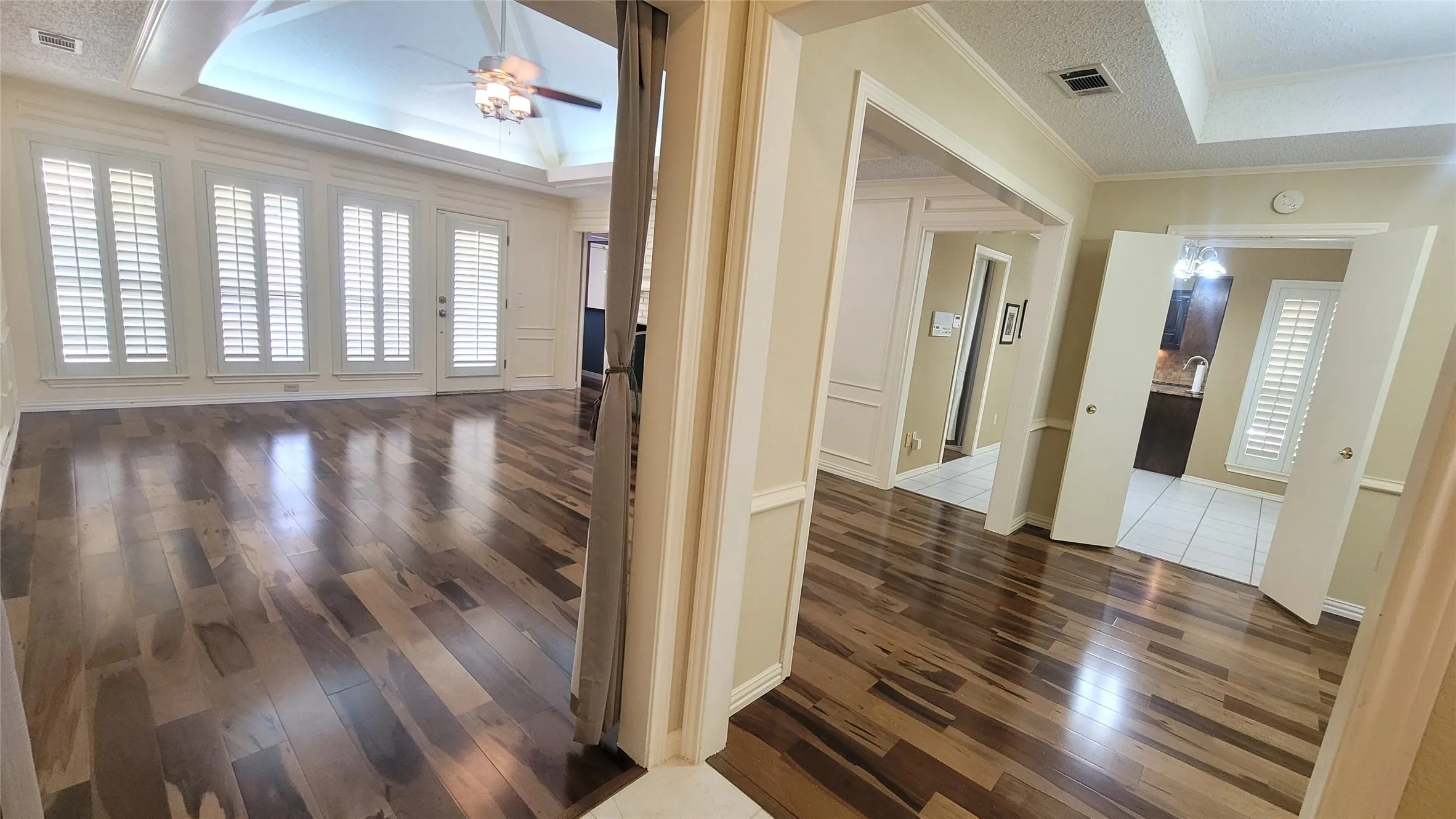 Wood-finish flooring, vaulted ceiling with recessed lighting, custom window shutters, tray ceilings, and double-door entry