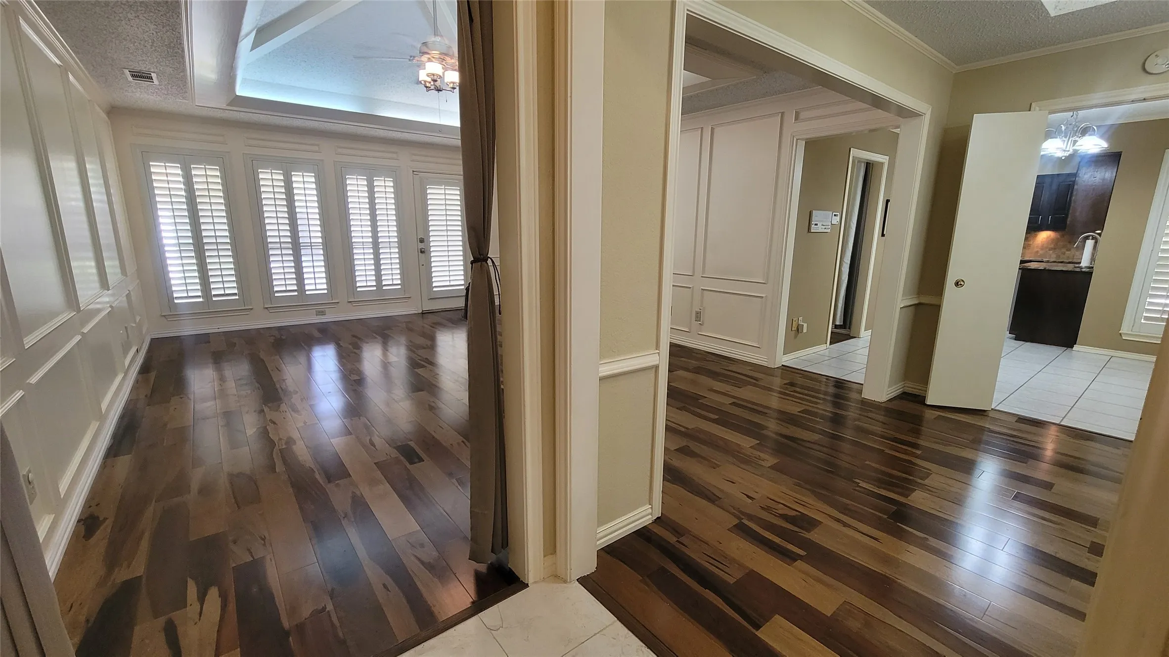 Wood-finish flooring, recessed wall paneling, plantation-style shutters, vaulted ceilings, and crown molding