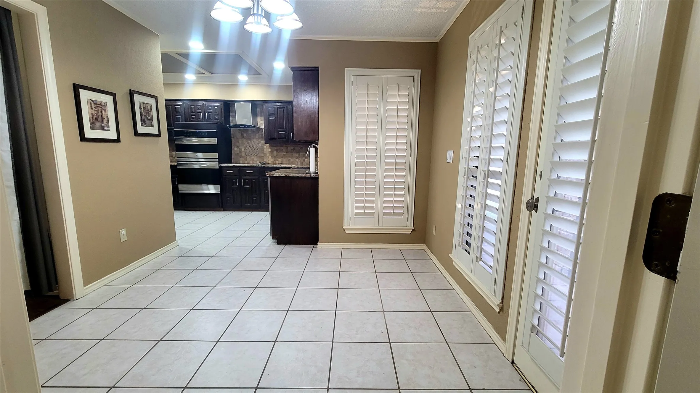 Tile flooring, custom dark wood cabinetry, built-in double ovens, and plantation shutters