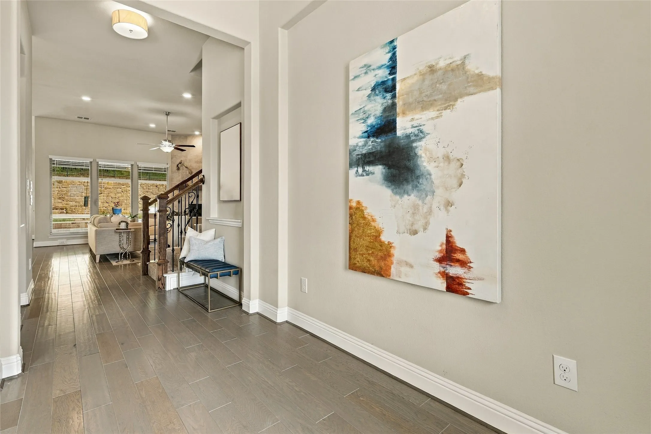 Foyer entry with wood-finish flooring, recessed ceiling lighting, and a dark-toned wood staircase with iron balusters