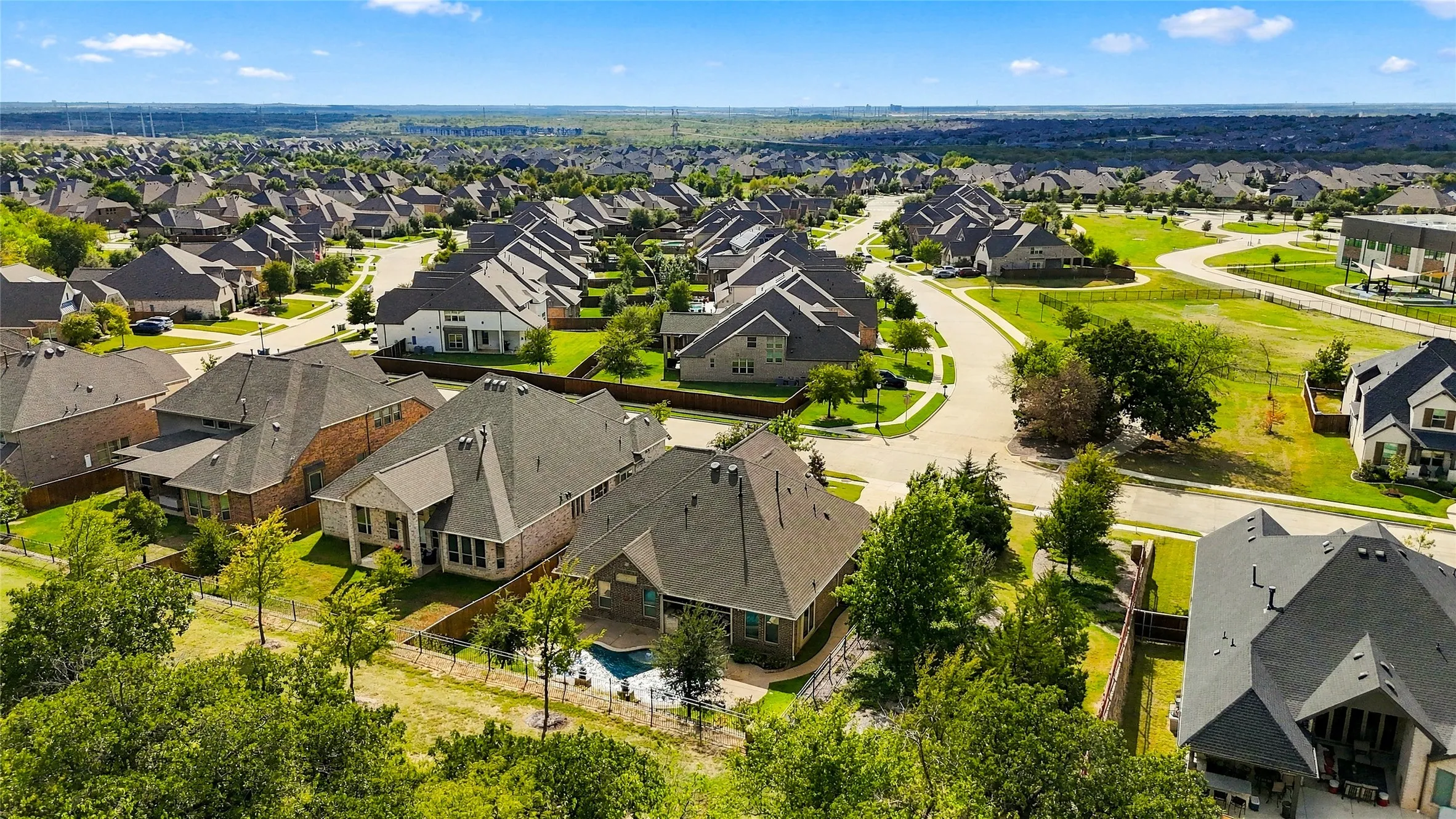 Aerial perspective of a residential property featuring a backyard swimming pool, brick and masonry siding, and a multi-pitch roof
