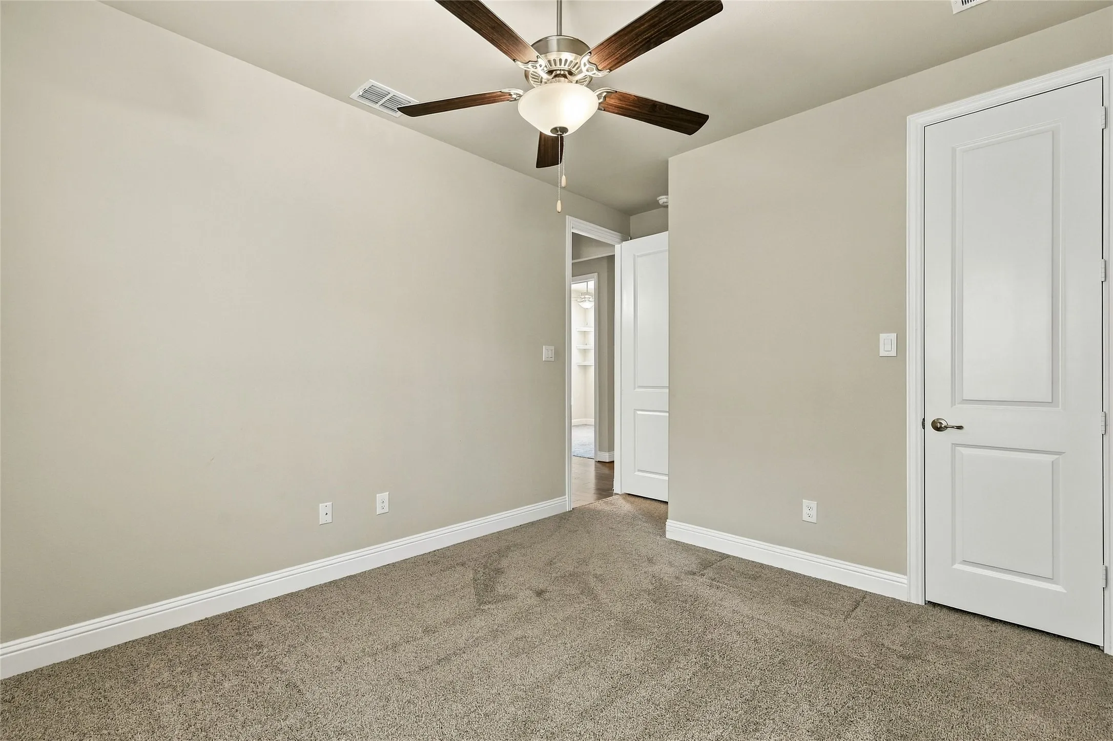 Neutral wall palette, wall-to-wall carpeting, ceiling fan with integrated lighting, and two-panel interior doors