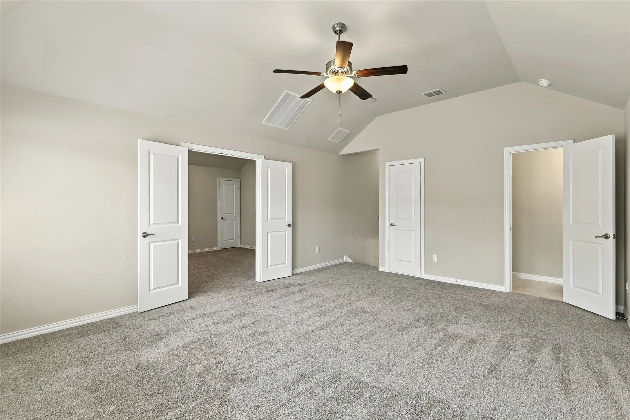 Vaulted ceiling featuring a ceiling fan with integrated lighting and neutral carpeting