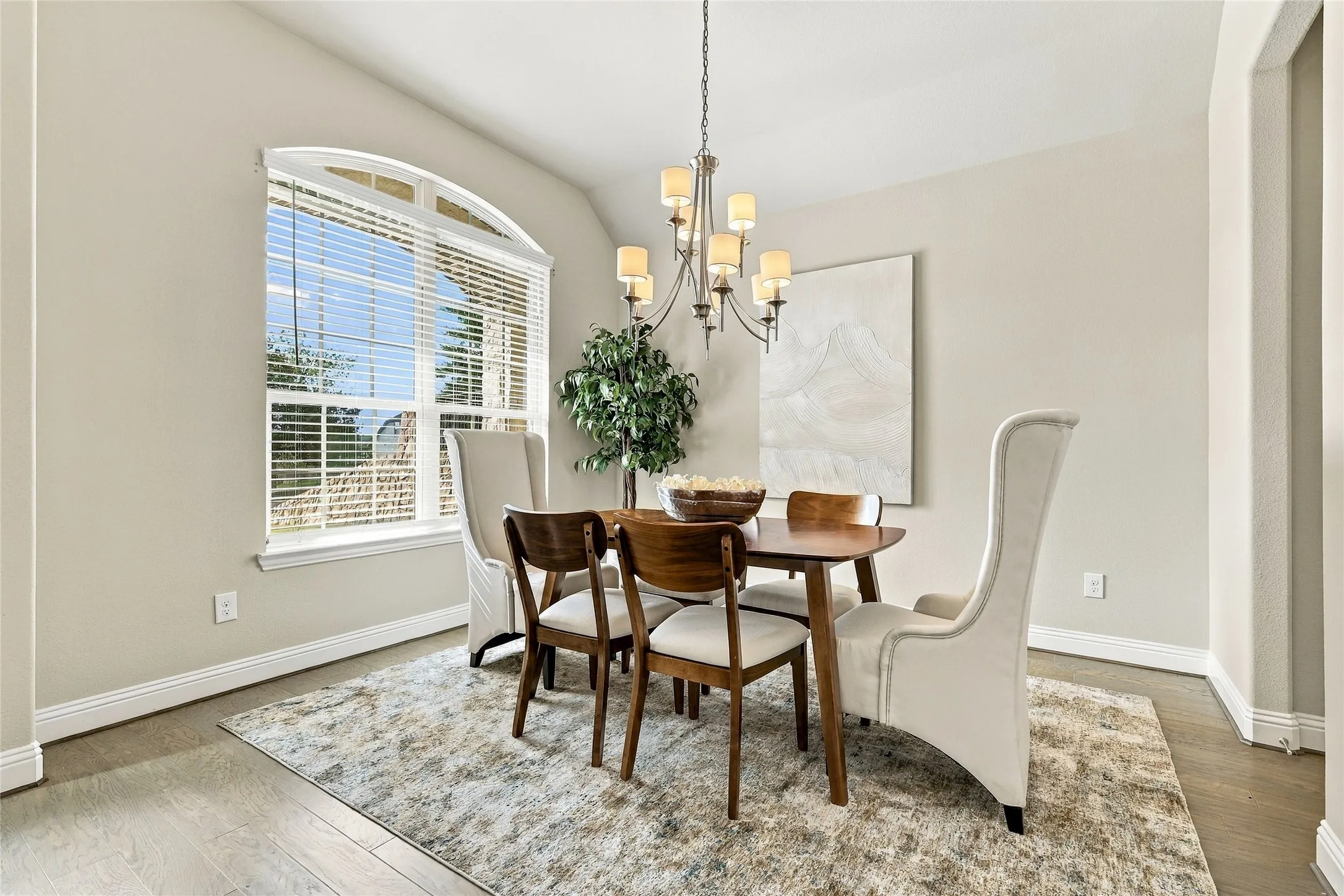 Dining area featuring wood-finish flooring, an arched window, and a multi-arm metal chandelier