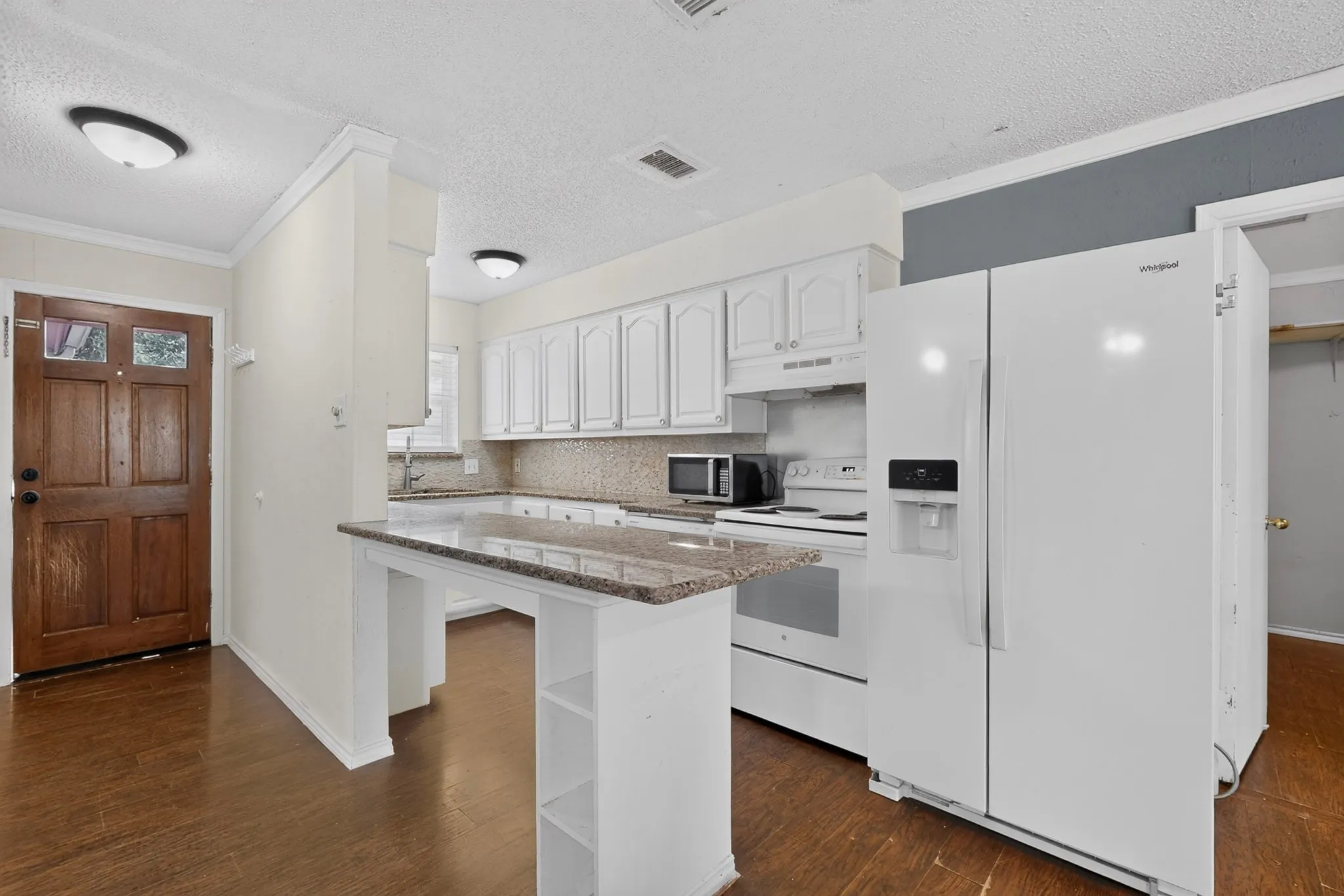 Kitchen featuring white cabinetry, stone-finish countertops, a raised breakfast bar, wood-finish flooring, and white appliances