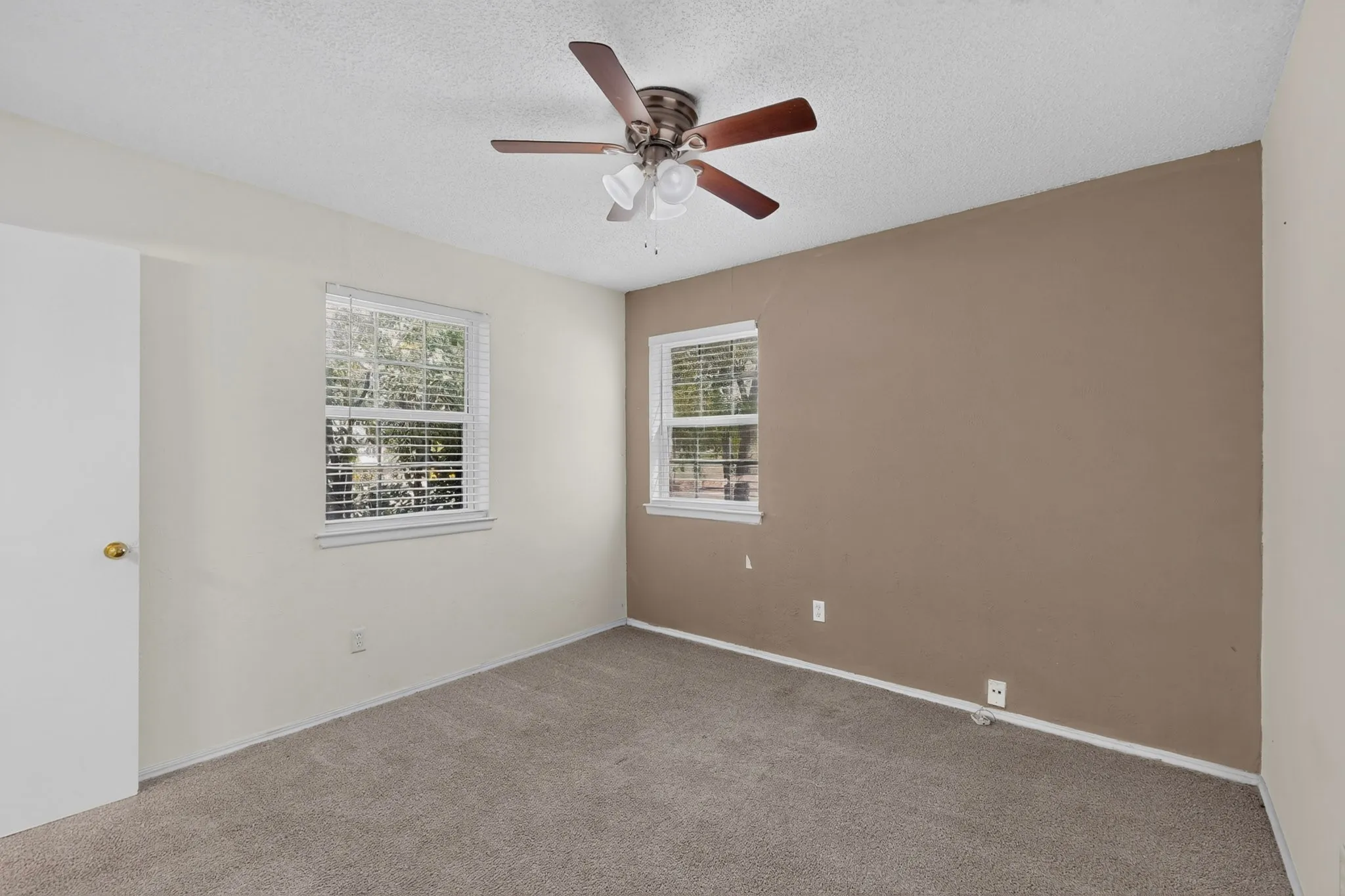 Interior space featuring carpeting, a ceiling fan with integrated lighting, and two windows with fitted blinds