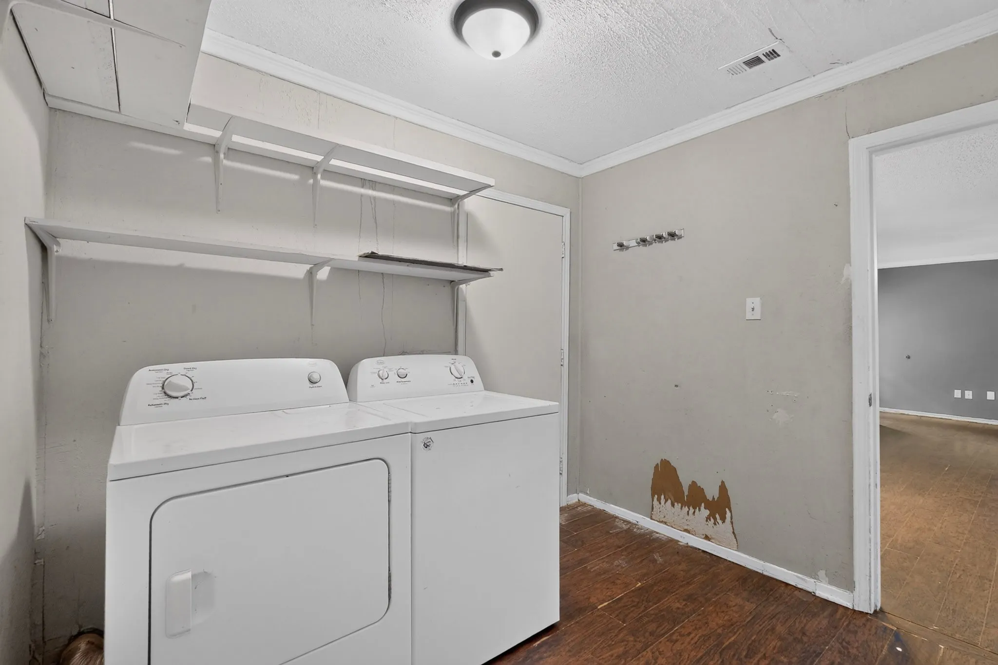 Utility room featuring wood-finish flooring, ceiling-mounted lighting, and built-in wall shelving