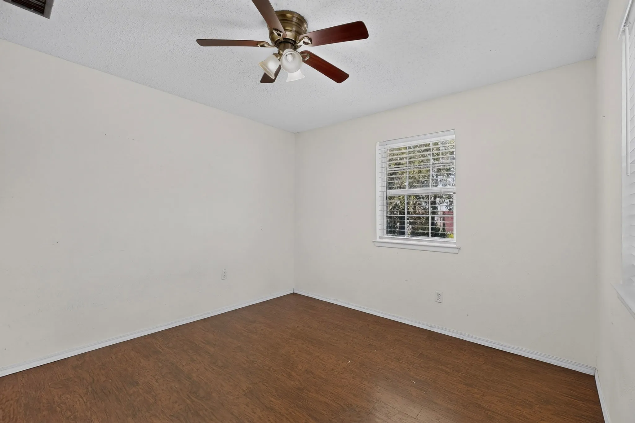 Room featuring wood-finish flooring, a multi-blade ceiling fan with integrated lighting, and a window with horizontal blinds