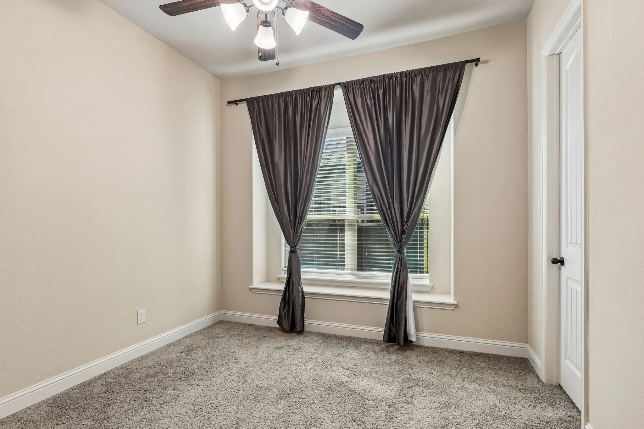 Neutral-toned interior featuring wall-to-wall carpeting, a recessed window with a built-in sill, a ceiling fan with integrated lighting, and a paneled interior door