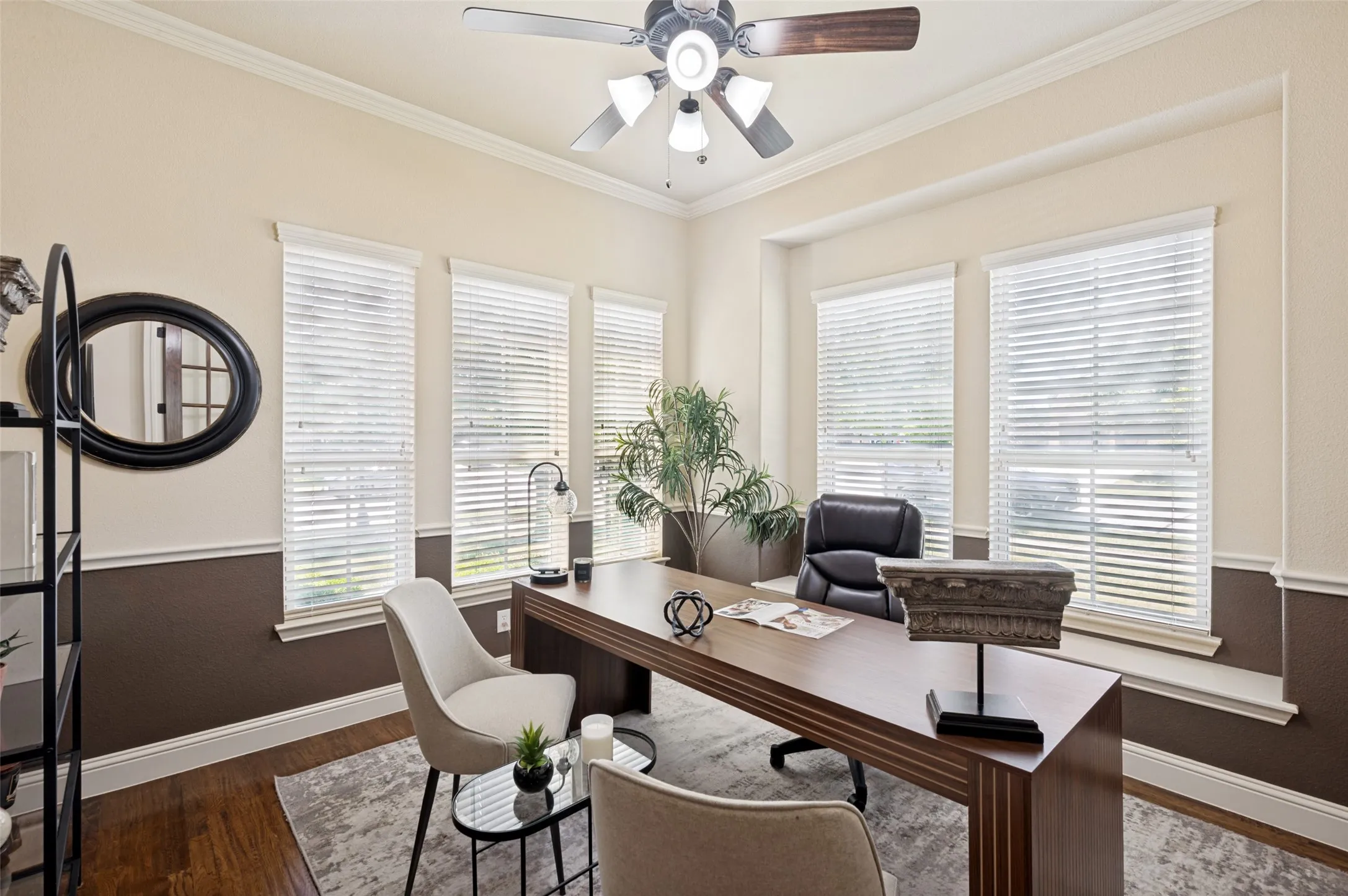 Room featuring wood-finish flooring, two-tone wall paint, chair rail molding, crown molding, and a ceiling fan with integrated lighting