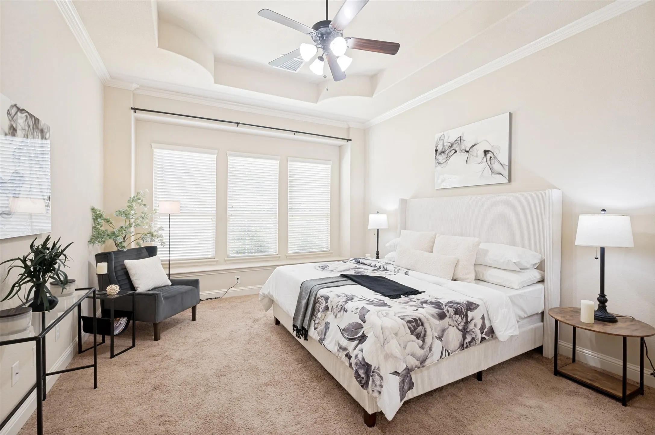 Tray ceiling featuring crown molding, triple window configuration, and an integrated ceiling fan