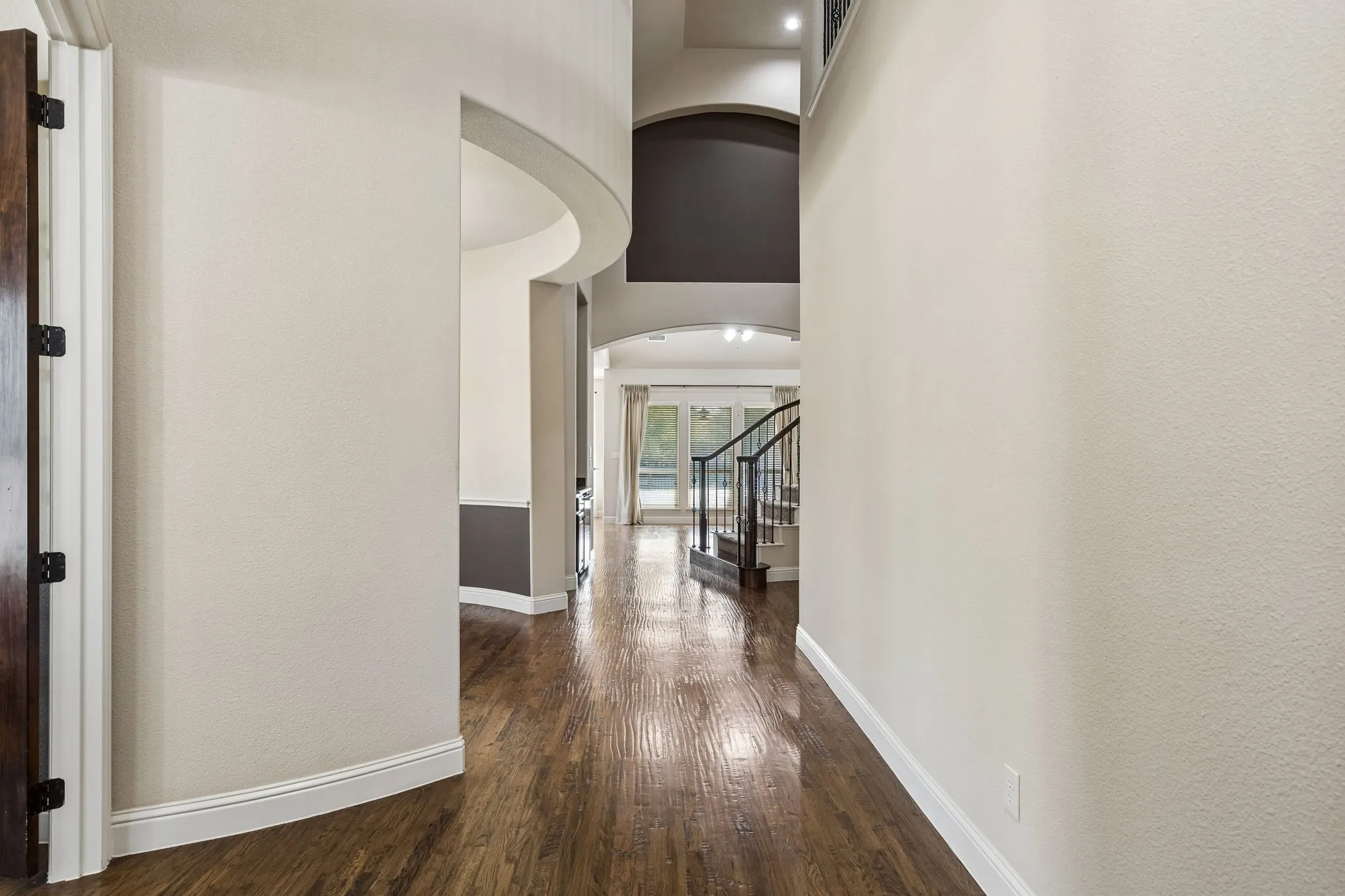 Foyer featuring wood-finish flooring, soaring ceilings with architectural archways, and a staircase with metal balusters