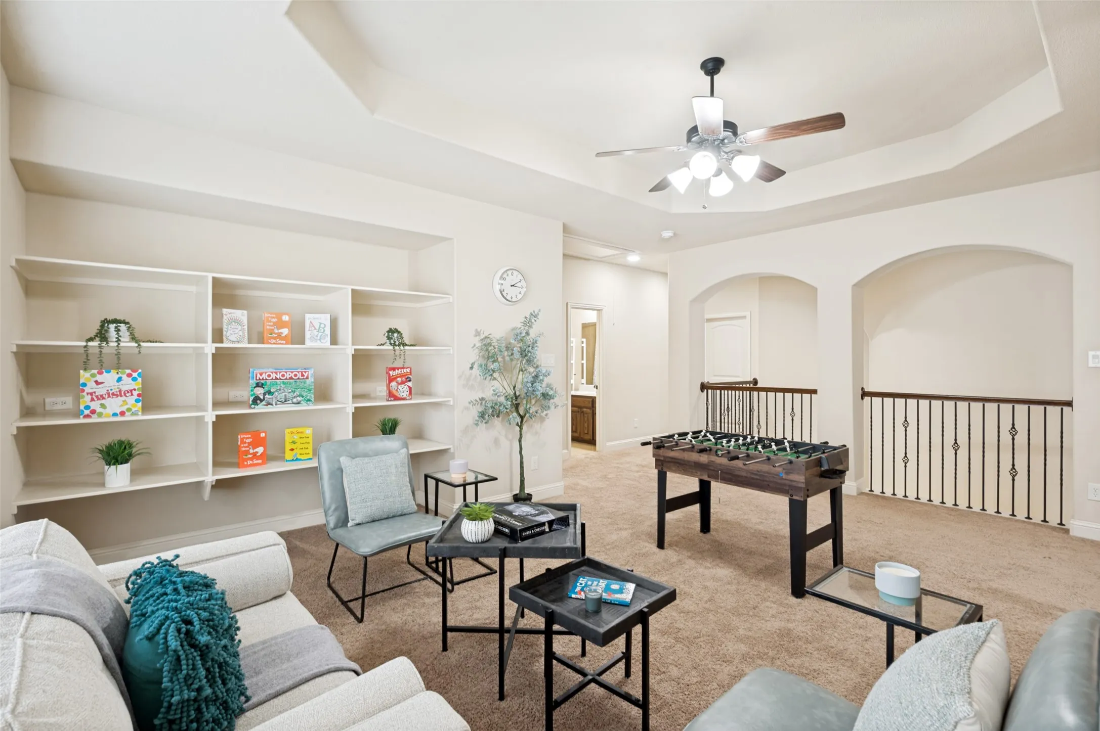 Tray ceiling with integrated lighting, built-in shelving, and metal stair railing