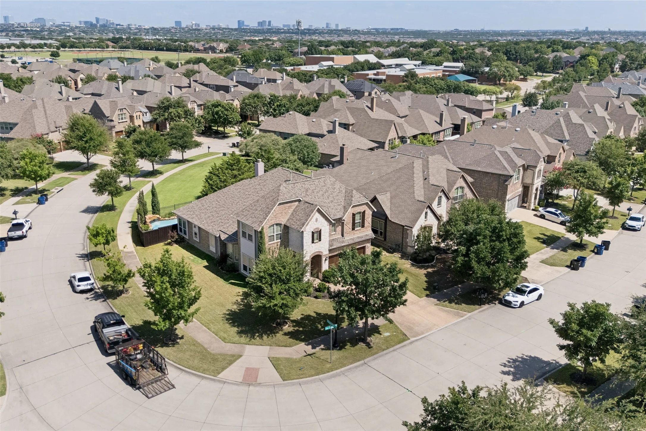 Corner lot residence featuring a multi-gabled roofline, stone and brick exterior, attached multi-car garage, and established landscaping