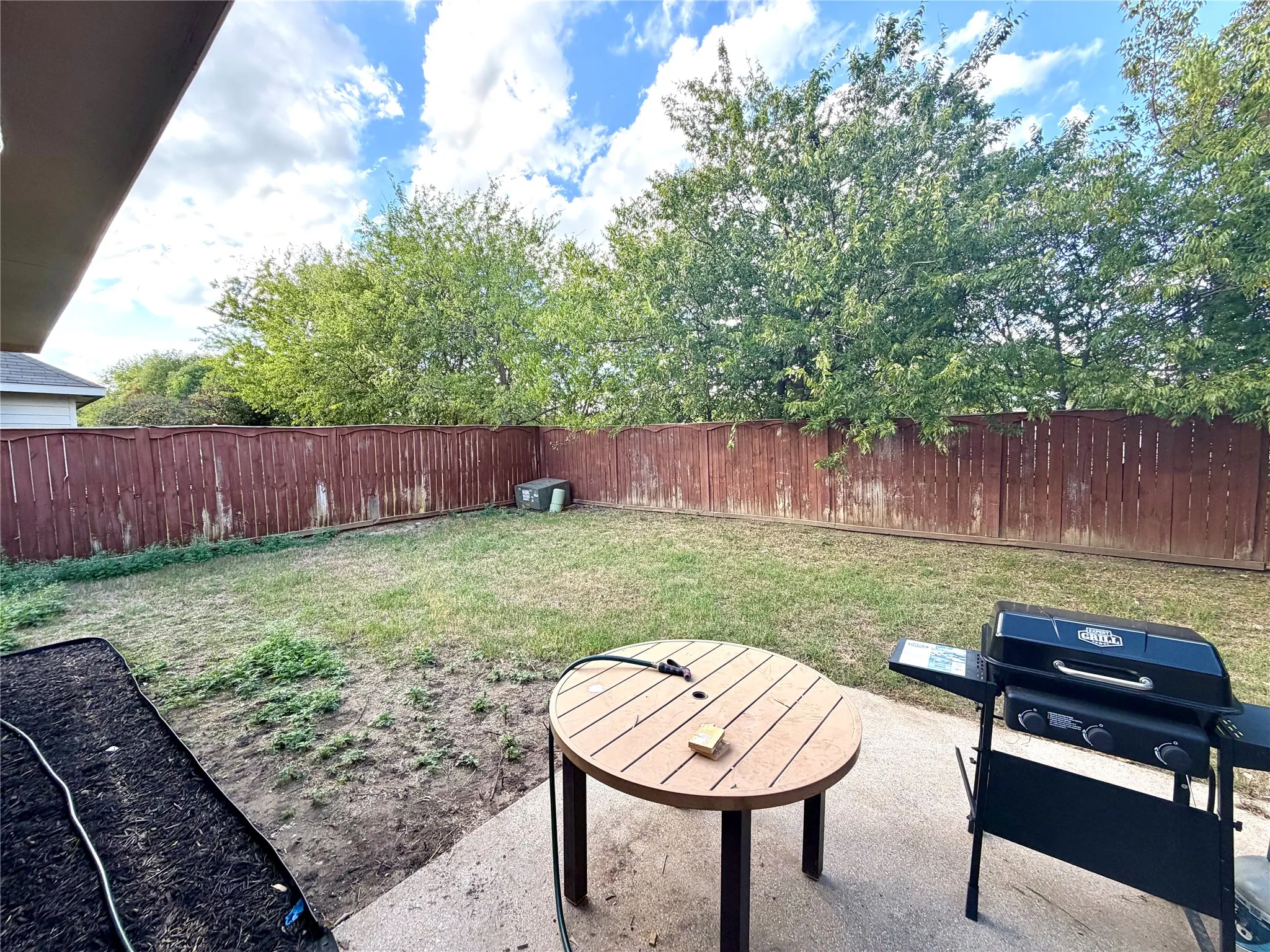 Backyard featuring a concrete patio, a lawn area, and a wood privacy fence