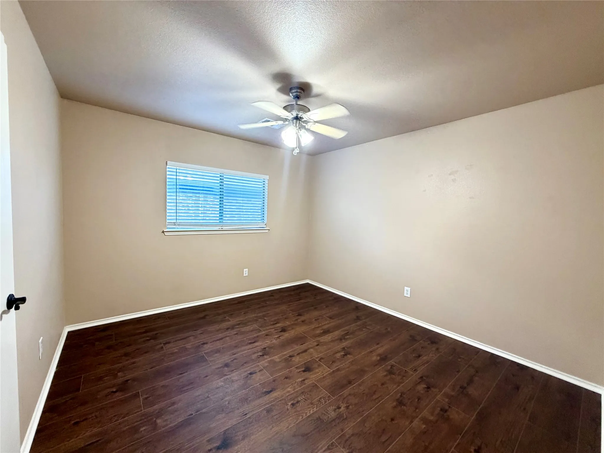 Room featuring wood-finish flooring, neutral wall paint, and a ceiling-mounted light fixture with an integrated fan
