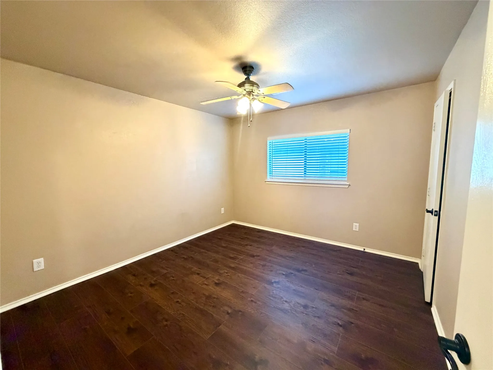 Room featuring wood-finish flooring, a ceiling fan with integrated lighting, and a single-pane window with horizontal blinds