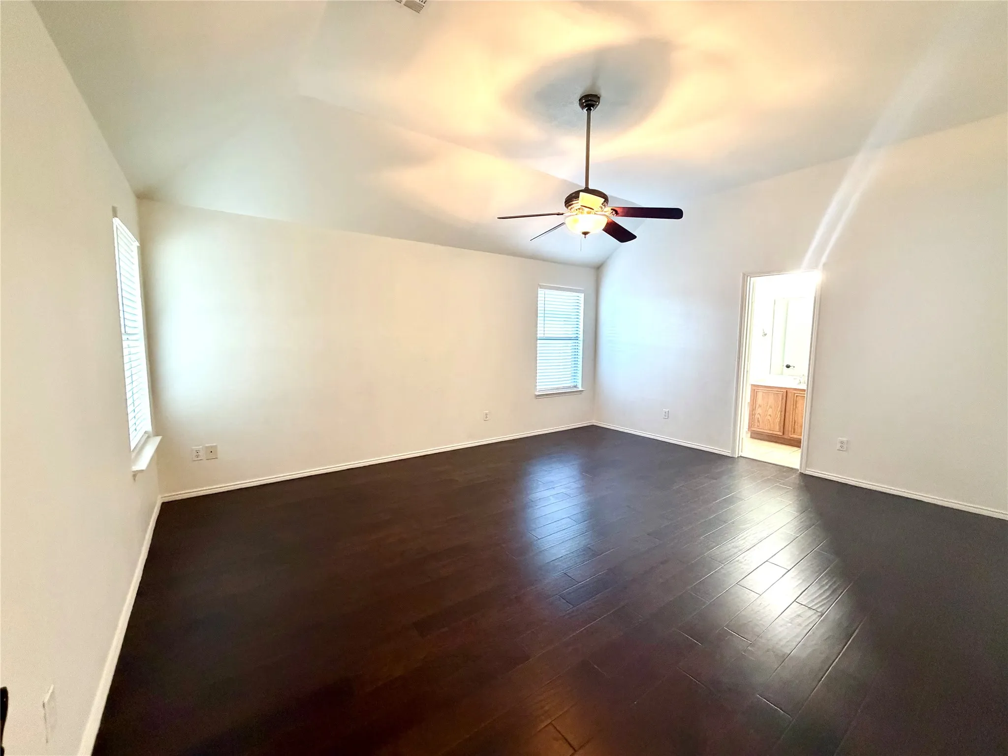 Vaulted ceilings, wood-finish flooring, dual windows, and an integrated ceiling fan with light fixture
