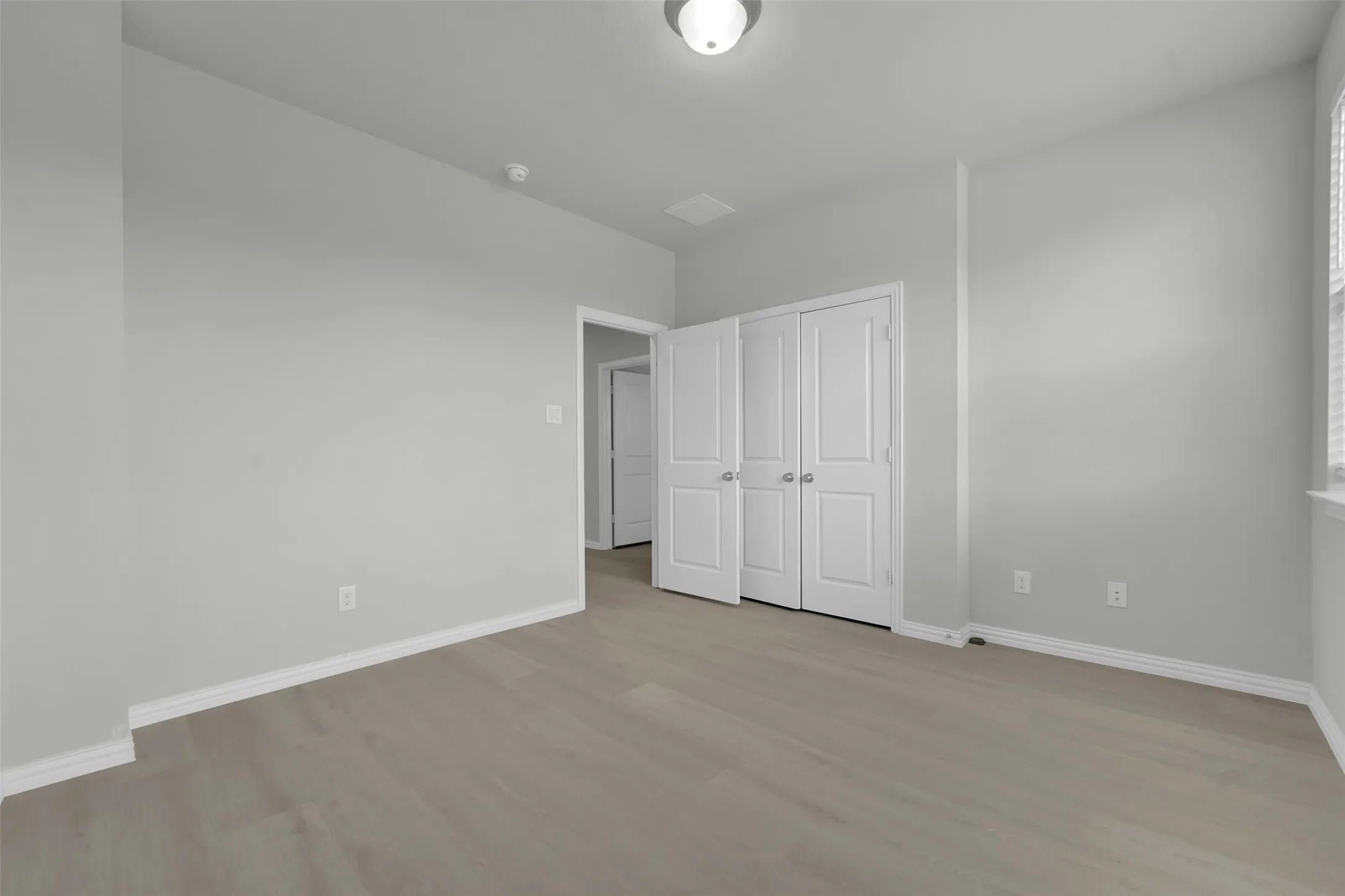 Wood-finish flooring, white bifold closet doors, and a ceiling-mounted light fixture