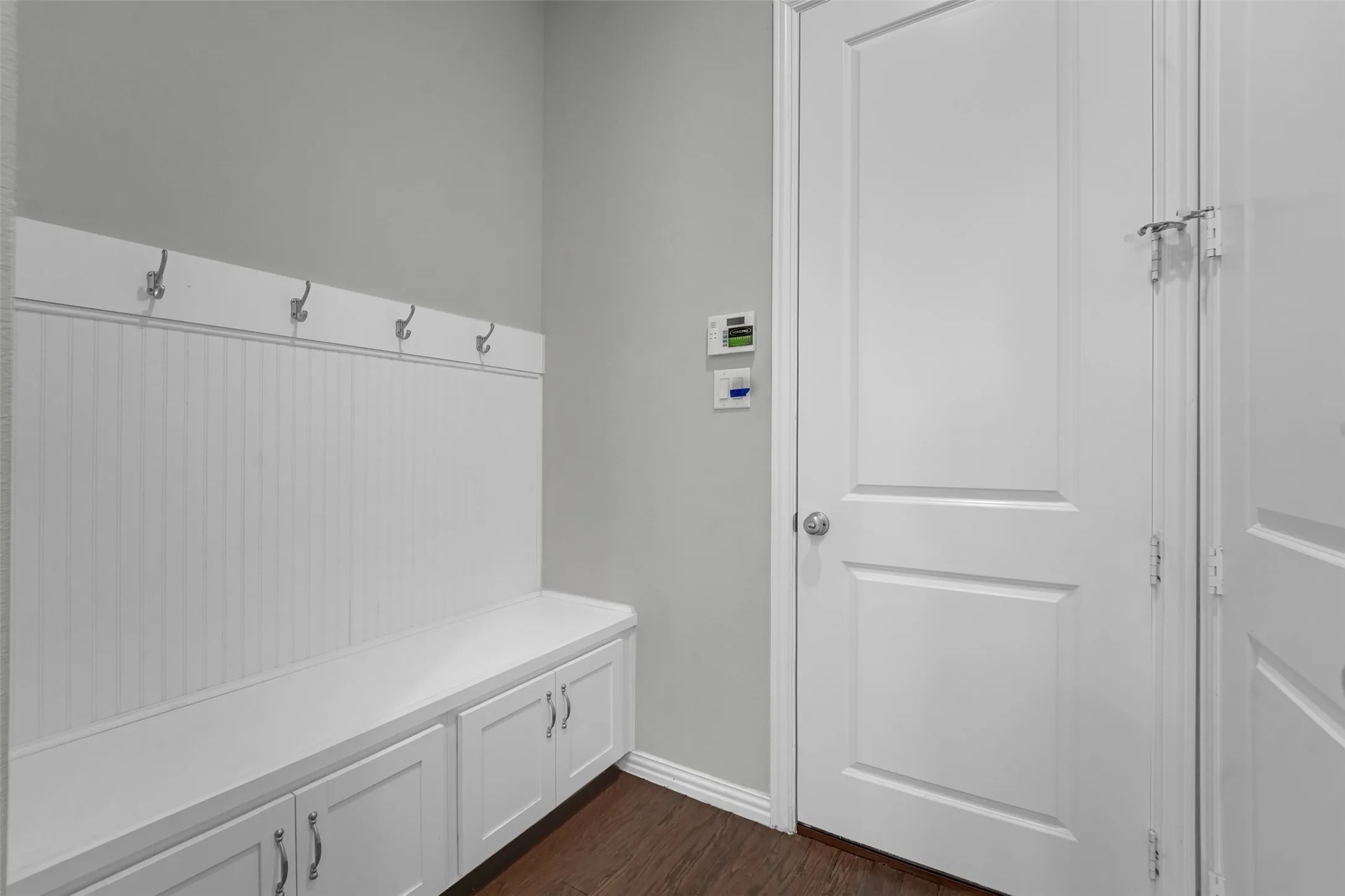 Built-in storage bench with cabinet doors, beadboard paneling, and wall-mounted hooks