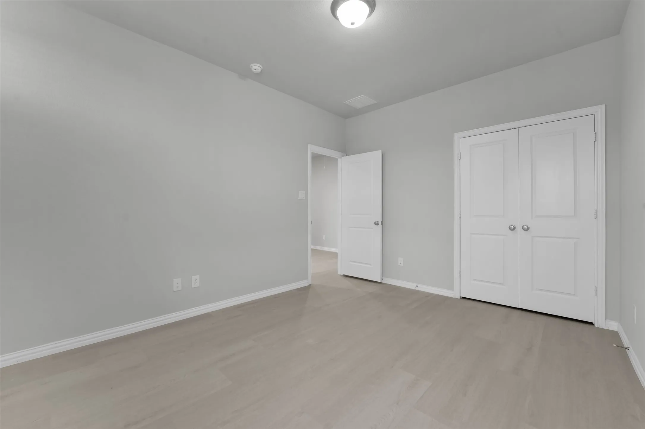 Light wood-finish flooring, white walls, white trim, and white bi-fold doors