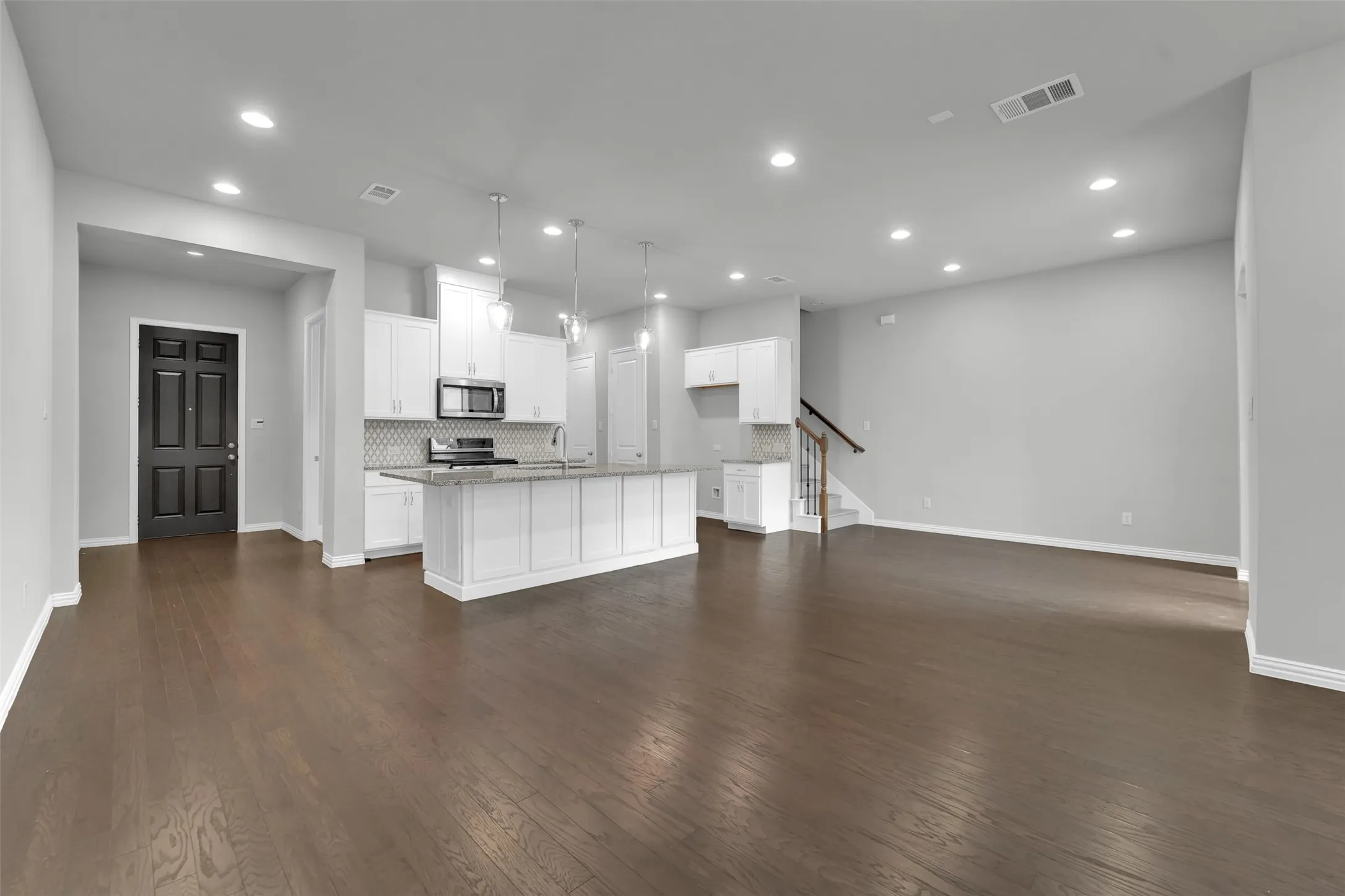 Open-concept living space featuring wood-finish flooring, recessed lighting, and a kitchen island with pendant lighting