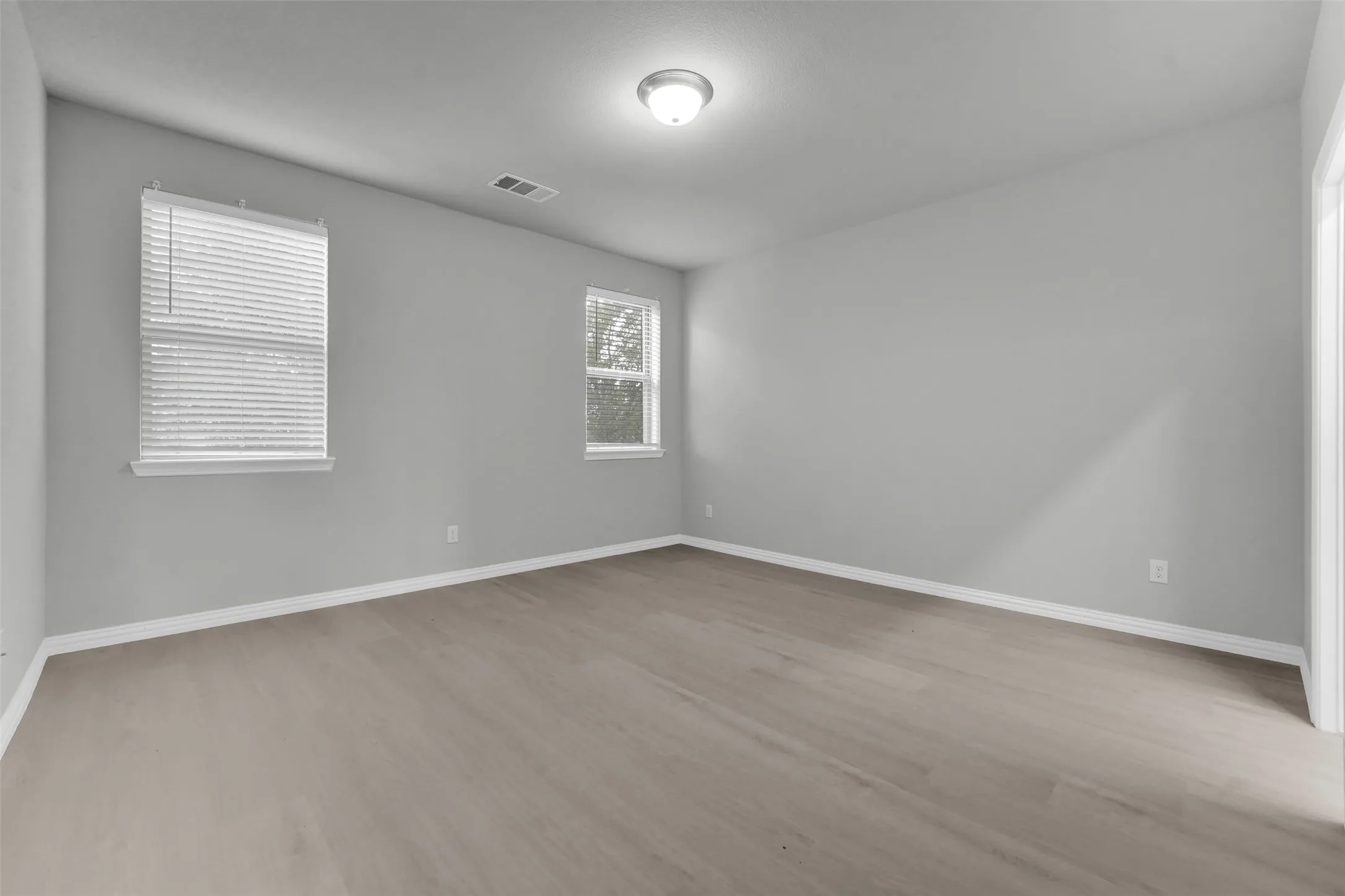 Wood-finish flooring, multiple windows with blinds, recessed lighting, and light gray wall finishes