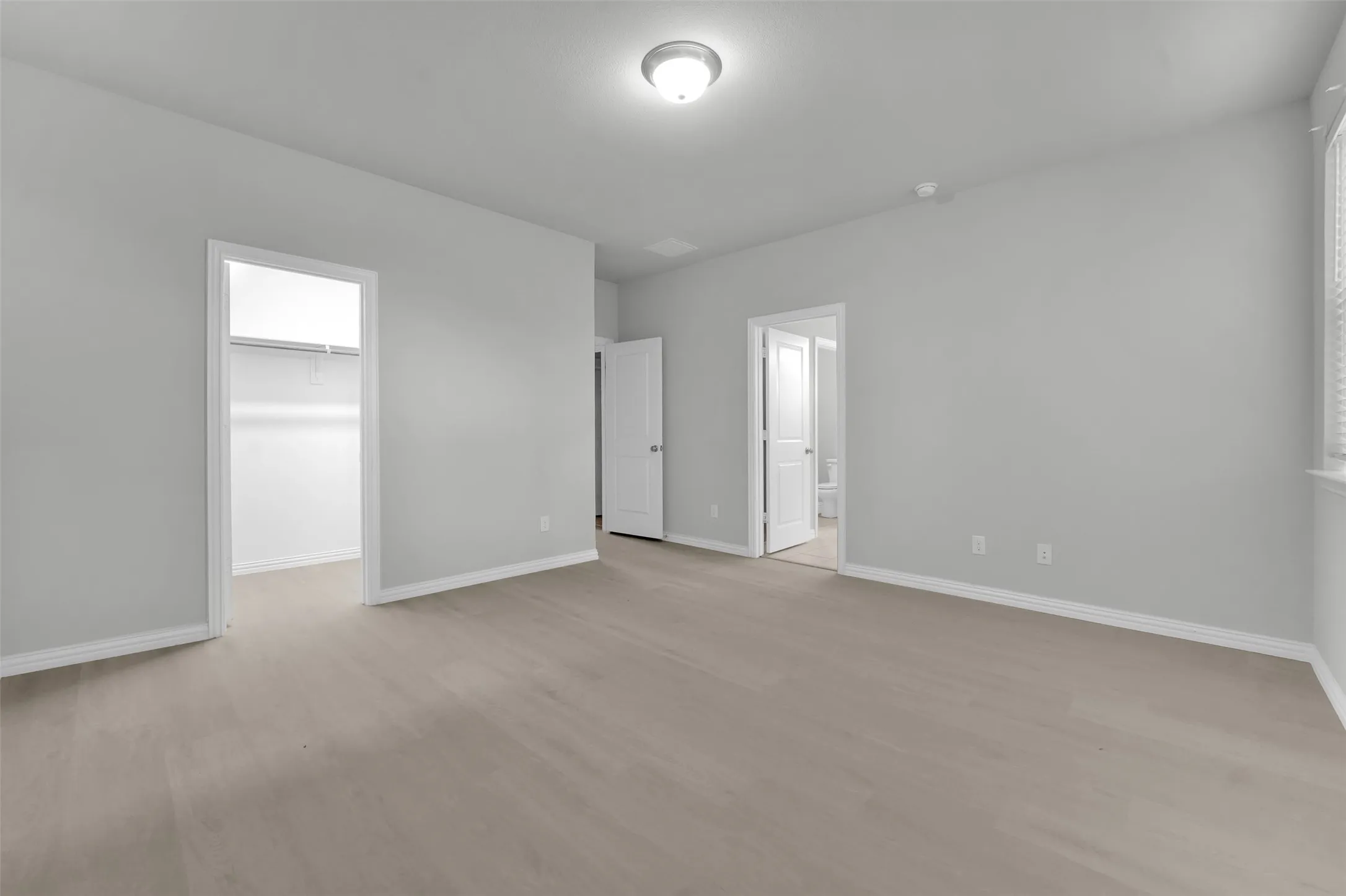 Spacious room with wood-finish flooring and neutral wall tones