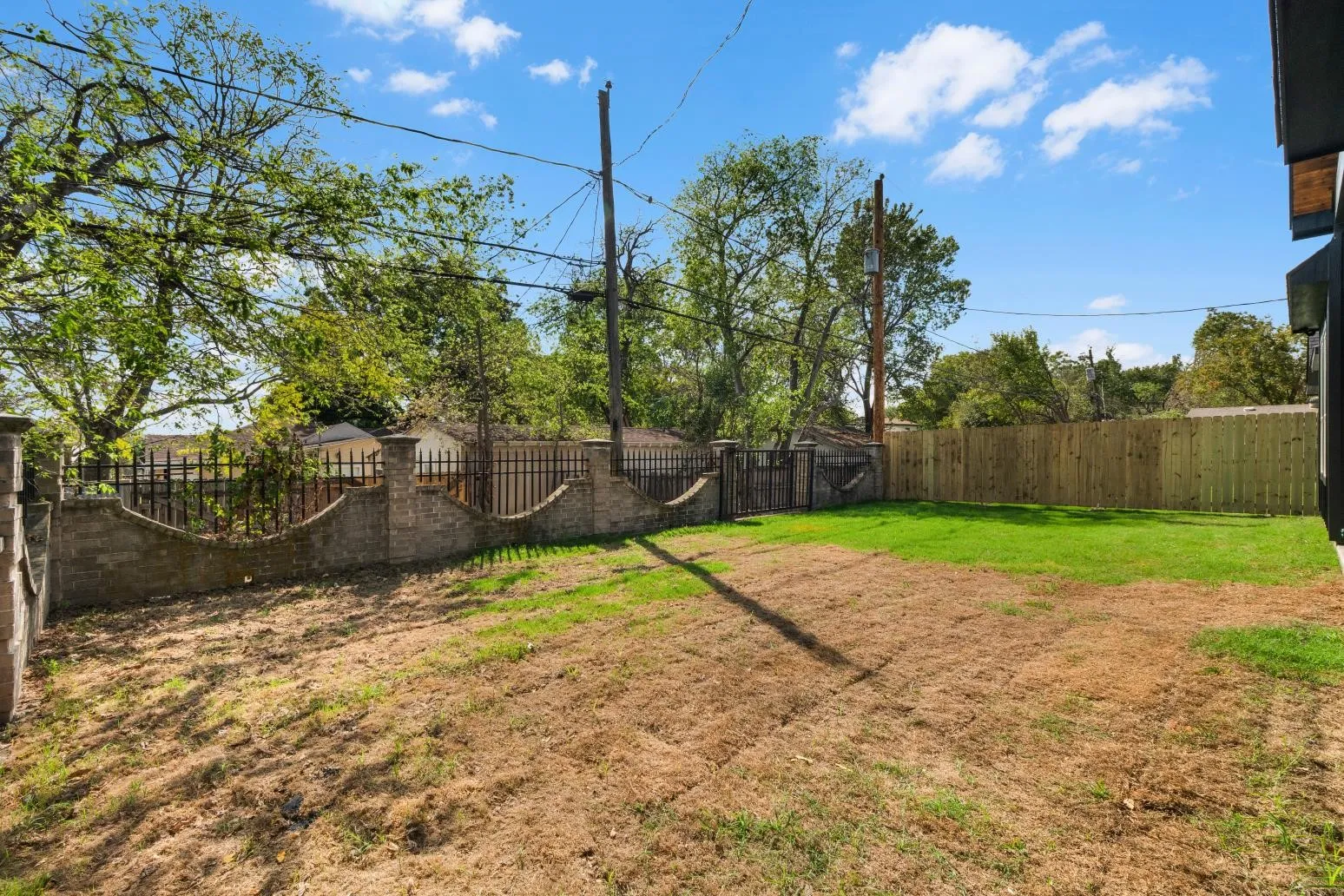 Backyard featuring a combination of masonry perimeter wall, ornamental iron fencing, and wood-panel privacy fencing