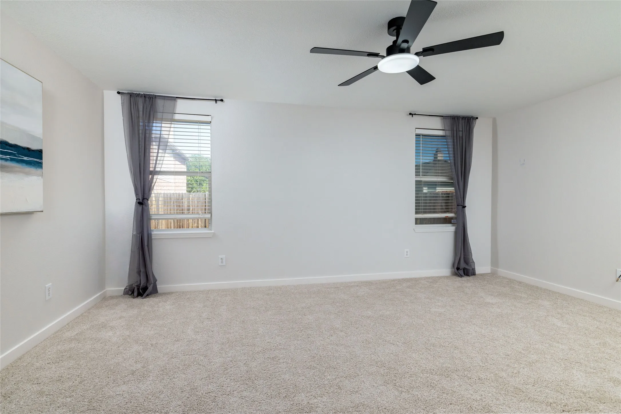Neutral-toned wall-to-wall carpeting, black multi-blade ceiling fan with integrated lighting, dual windows with integrated blinds, and light-toned wall finish