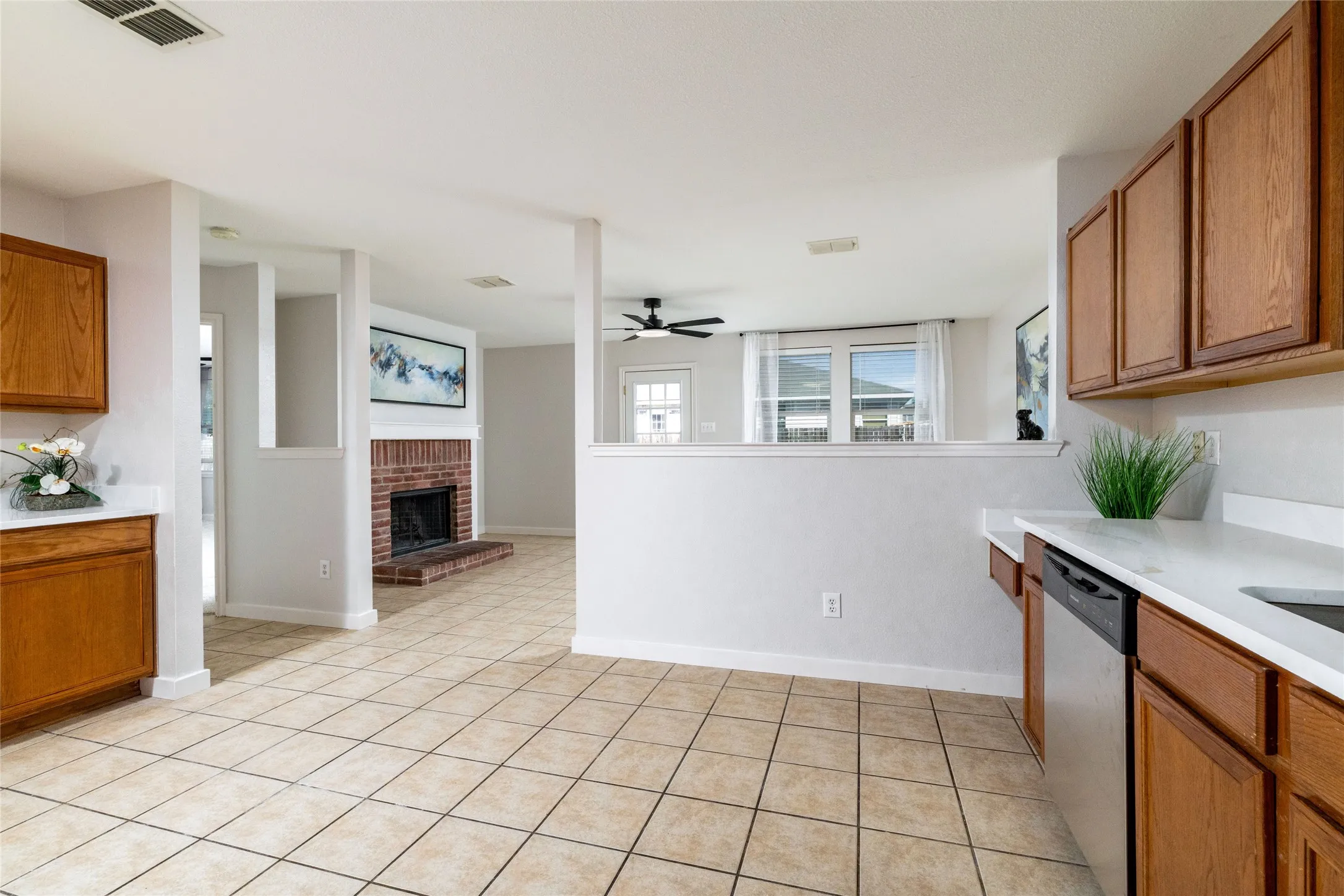 Kitchen featuring wood cabinetry, white countertops, tile flooring, and a brick fireplace