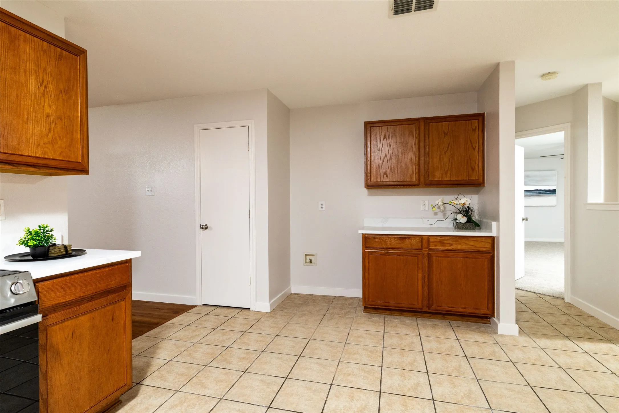 Kitchen featuring wood cabinetry, white countertops, tile flooring, and a dedicated storage closet