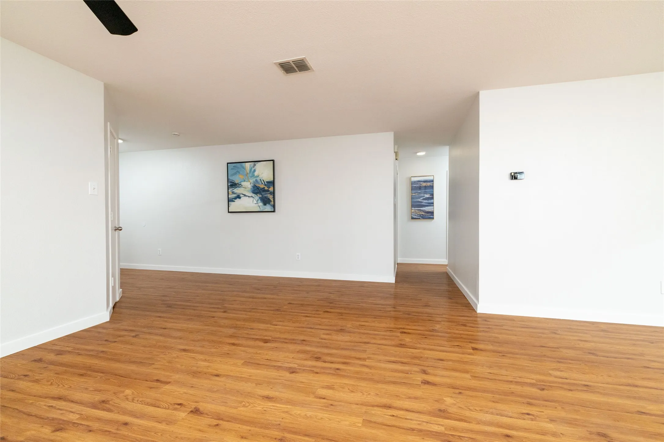 Open-concept interior featuring wood-finish flooring, neutral walls, and a ceiling-mounted fan