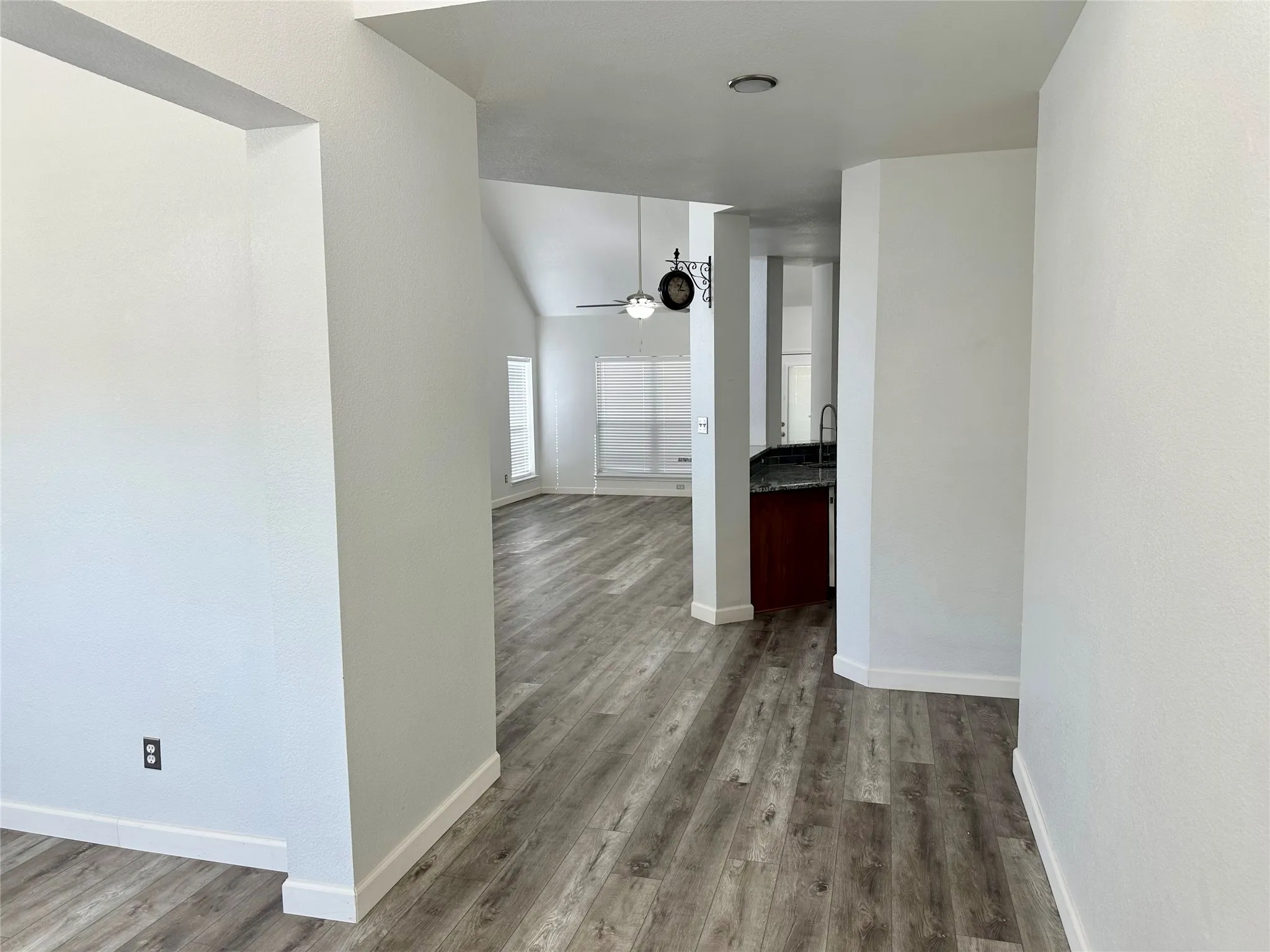 Wood-finish flooring, vaulted ceilings, and kitchen cabinetry with stone-finish countertops