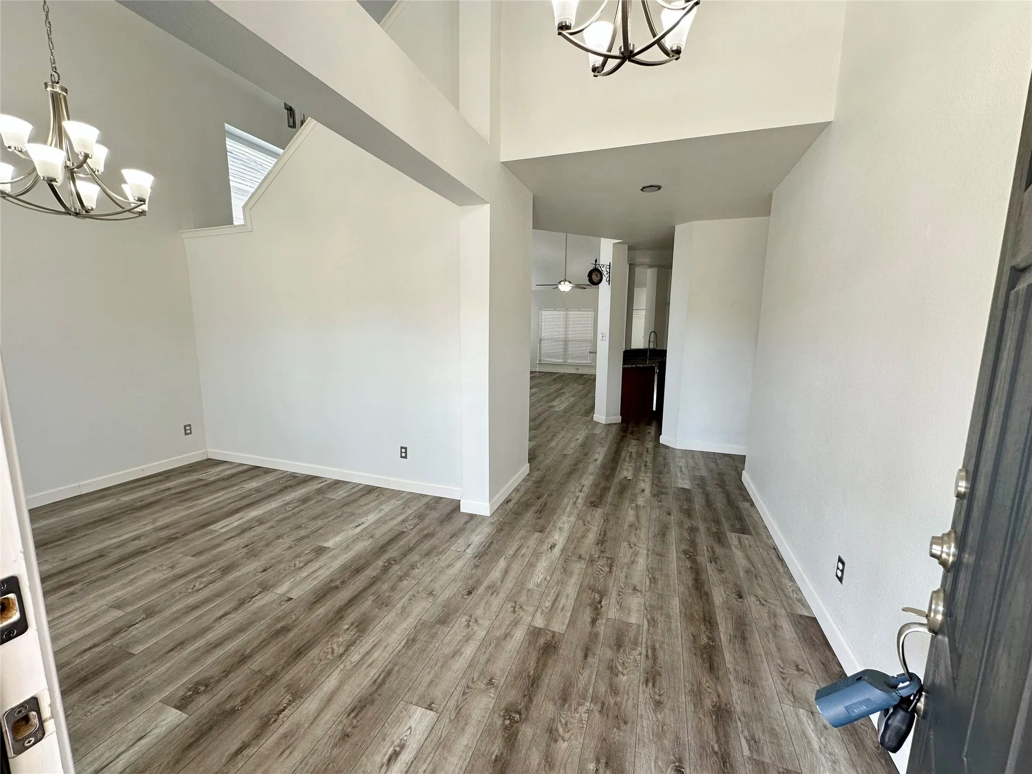 Vaulted ceilings, wood-finish flooring, and multi-arm chandelier lighting