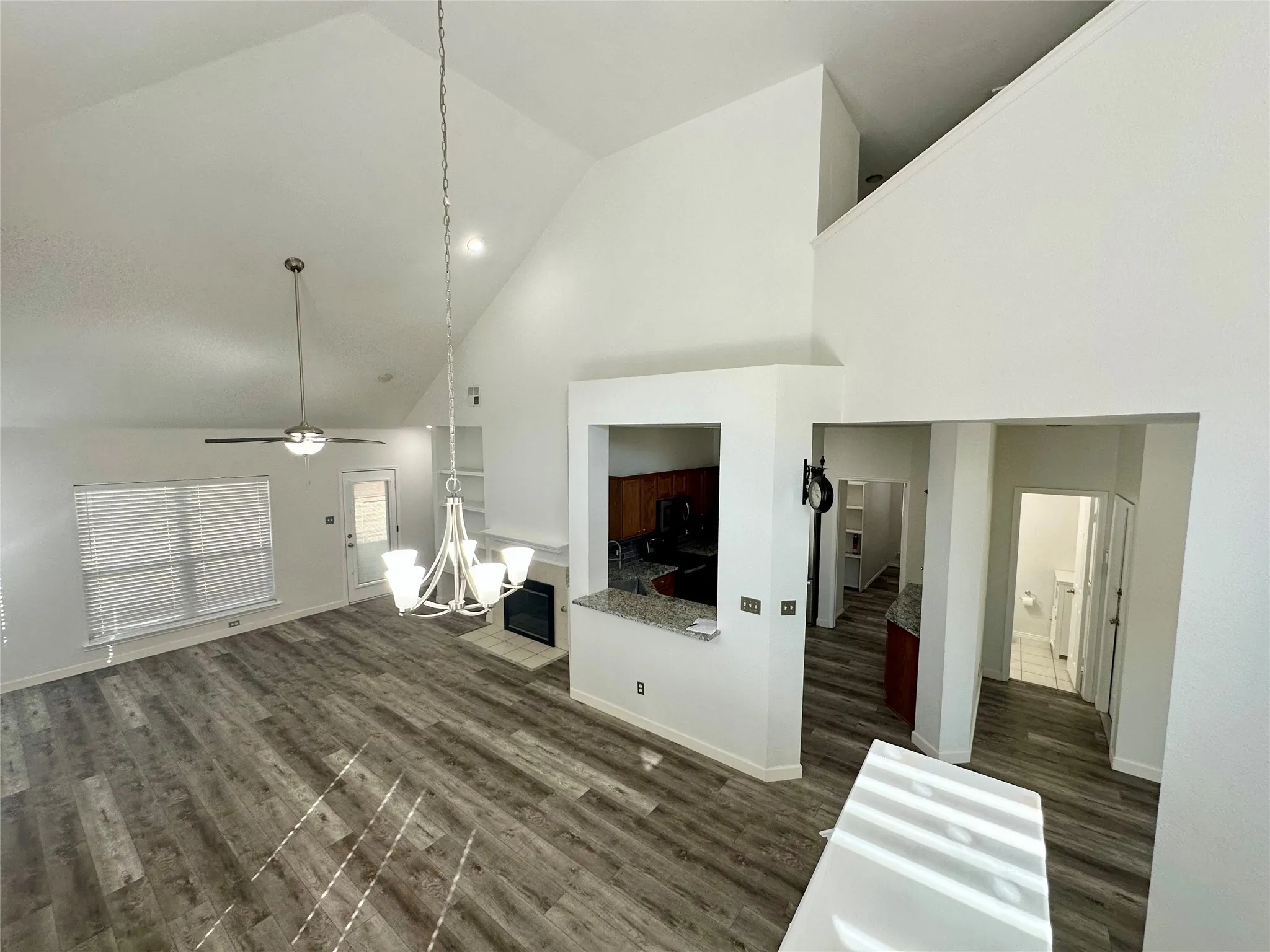 Vaulted ceilings, wood-finish flooring, built-in fireplace, and overhead lighting fixtures
