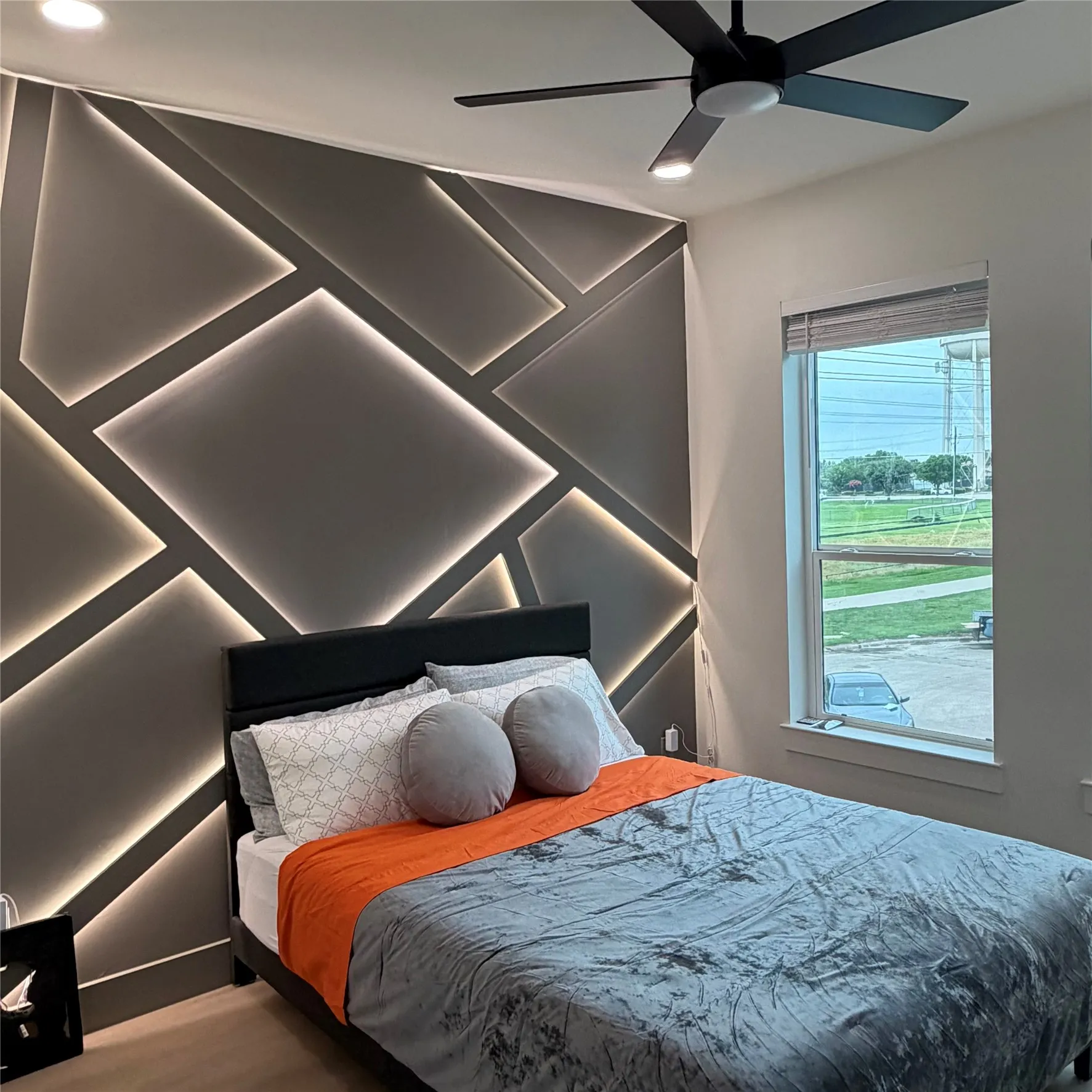 Custom accent wall featuring geometric paneling with integrated recessed lighting, recessed ceiling lighting, and a modern matte black ceiling fan