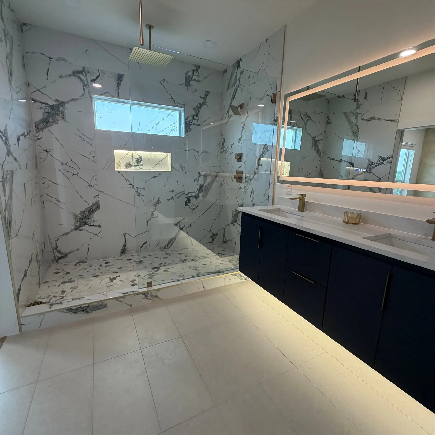 Floating vanity featuring dark cabinetry, dual integrated sinks, and under-cabinet lighting