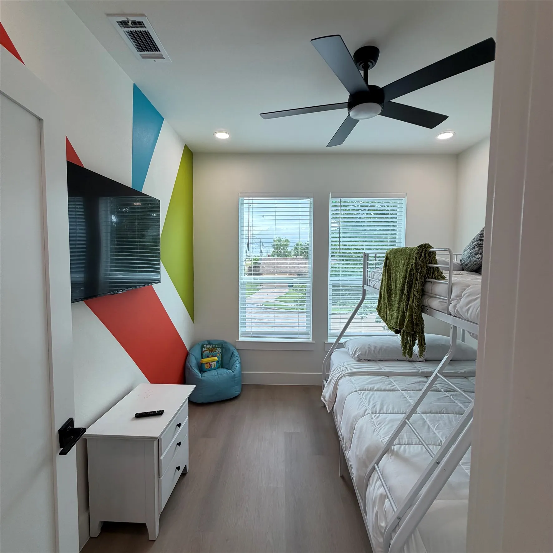 Wood-finish flooring, matte black ceiling fan with integrated lighting, dual windows with blinds, and recessed lighting