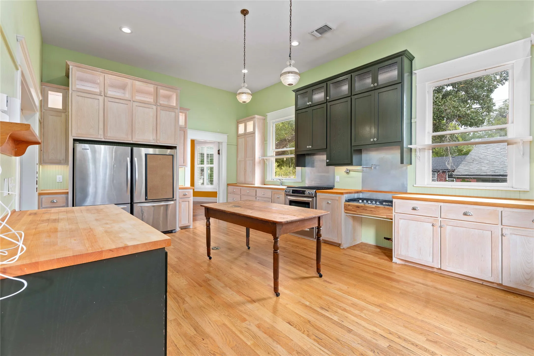 Kitchen featuring two-tone custom cabinetry, butcher block countertops, stainless steel appliances, recessed lighting, and wood-finish flooring