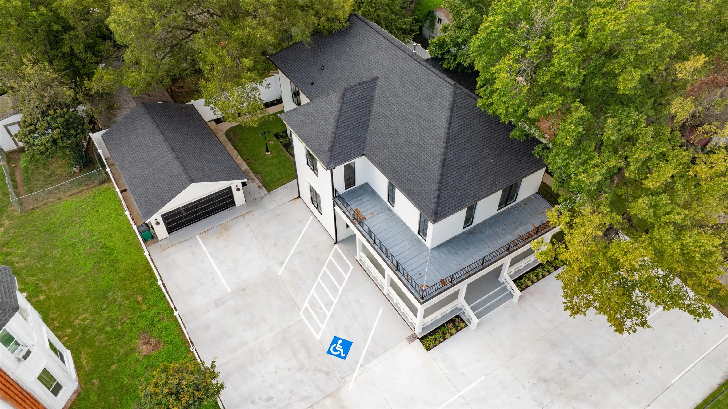 Aerial view showcasing the two-story structure featuring a dark-toned shingle Aerial view showcasing the two-story structure, new roof, crisp white exterior, and a paved parking area