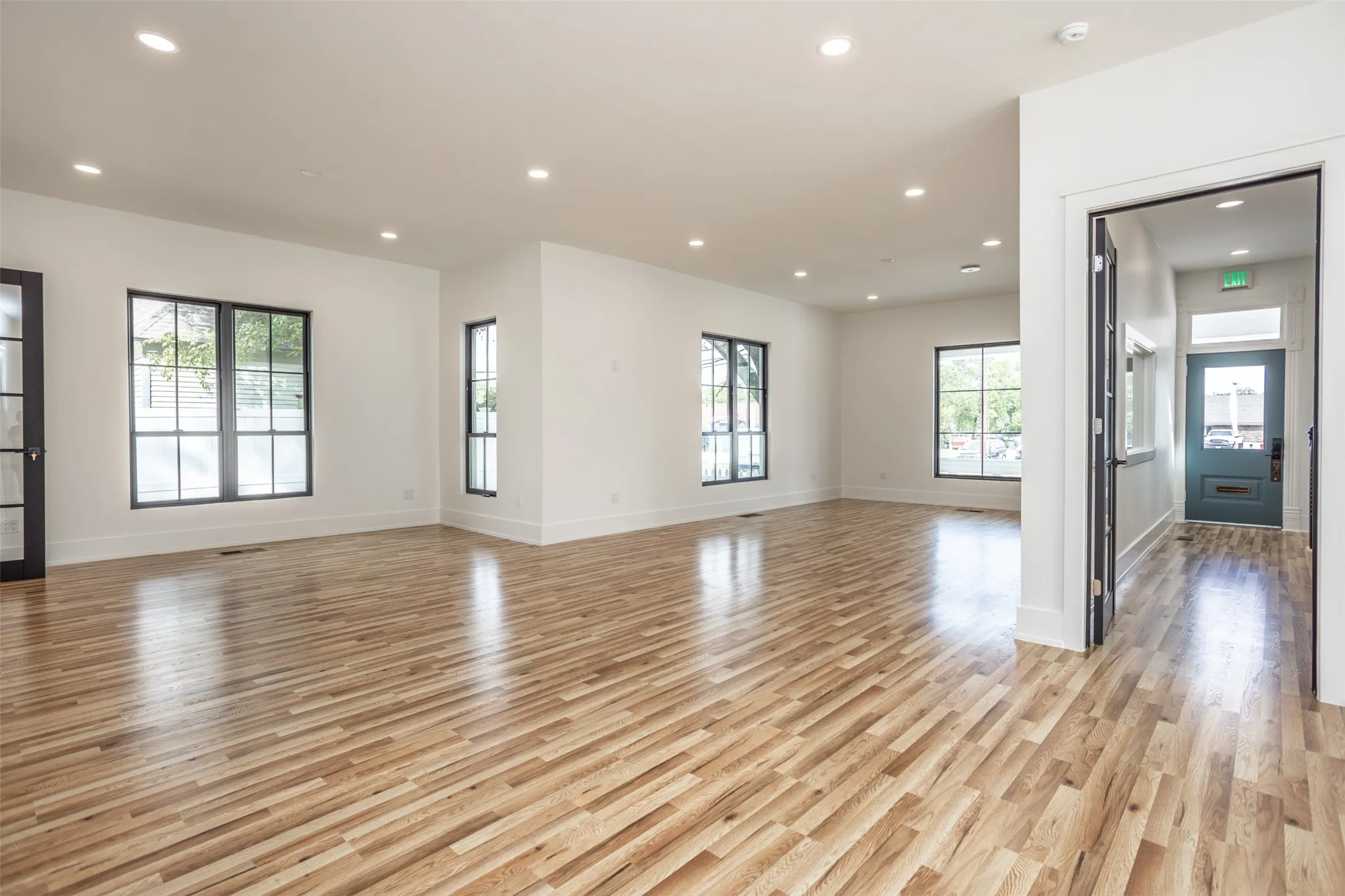 Open floor plan featuring wood-finish flooring, recessed lighting, multi-pane windows, and neutral interior paint