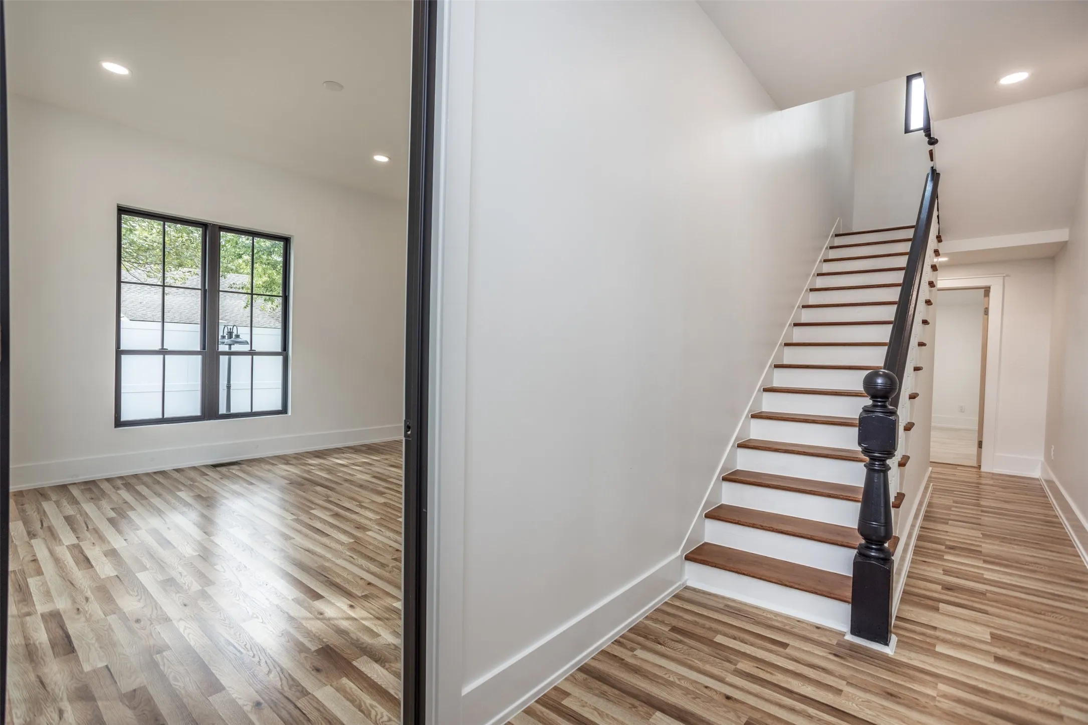 Staircase featuring wooden treads, white risers, and a dark-finished newel post, wood-finish flooring throughout, and grid-pane windows