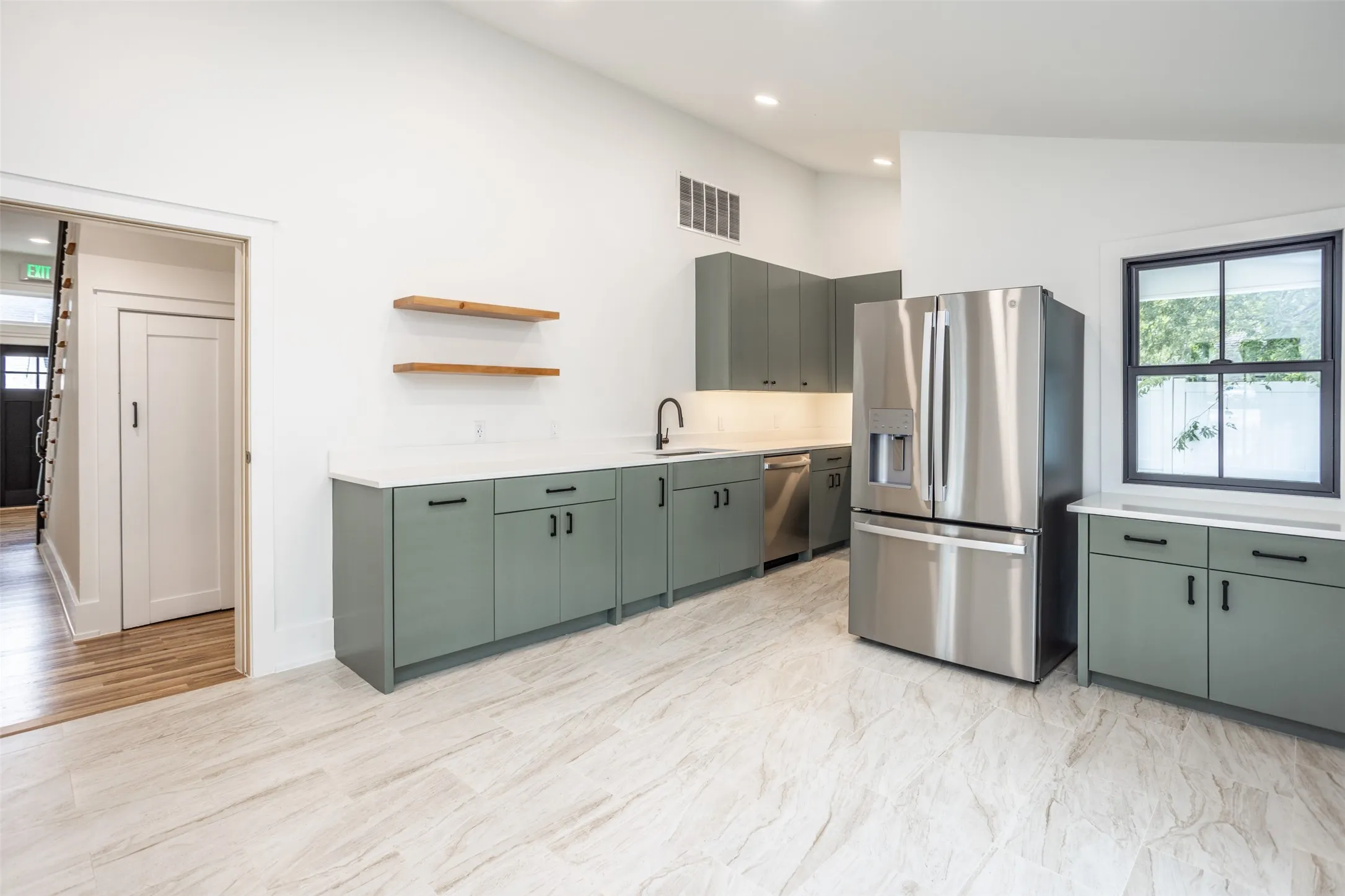 Kitchen featuring new custom cabinetry, countertops, stainless steel appliances, open wood shelving, and tiled flooring